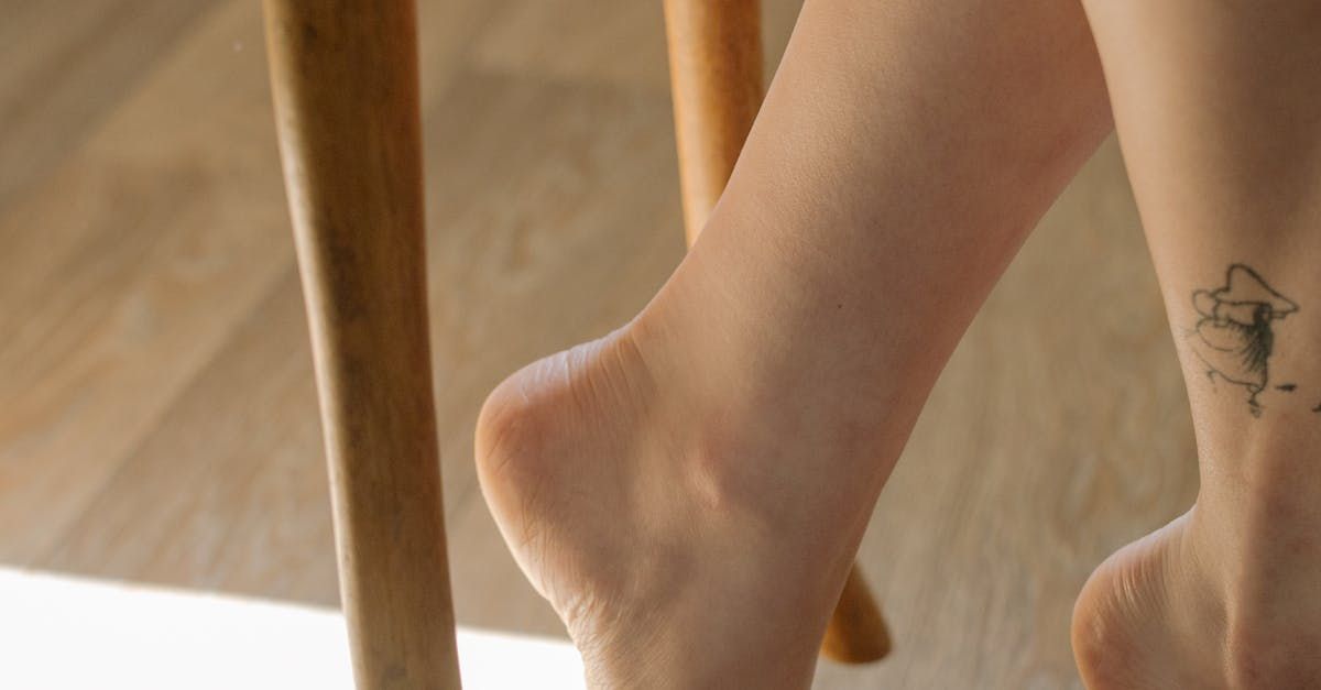 A woman with a tattoo on her ankle is sitting on a chair.