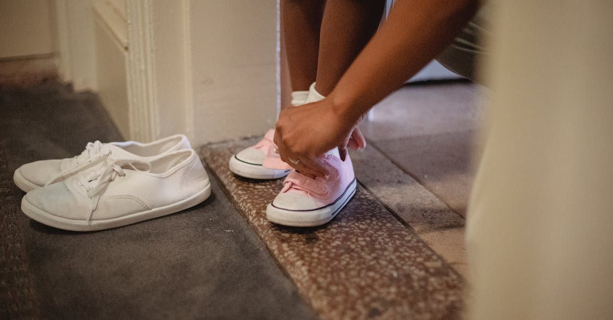 A woman is tying her shoes on a tiled floor.