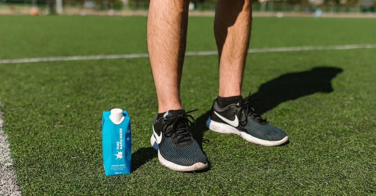 A person is standing on a soccer field next to a bottle of water.