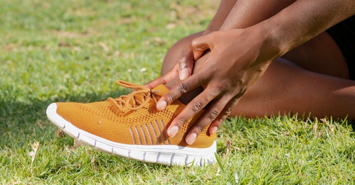 A person is tying their shoes while sitting on the grass.
