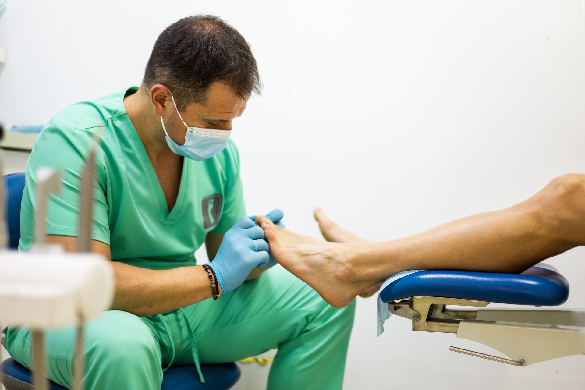 A doctor is examining a patient 's foot in a dental chair.