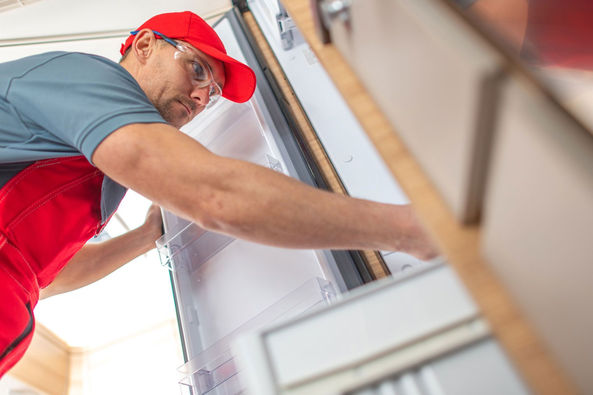 Man in red hat and overalls installing window frame.