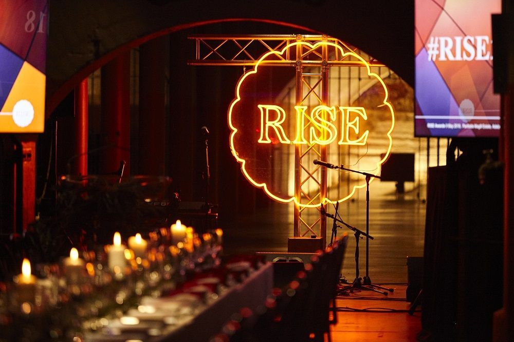 A stage with a neon sign that says rise on it