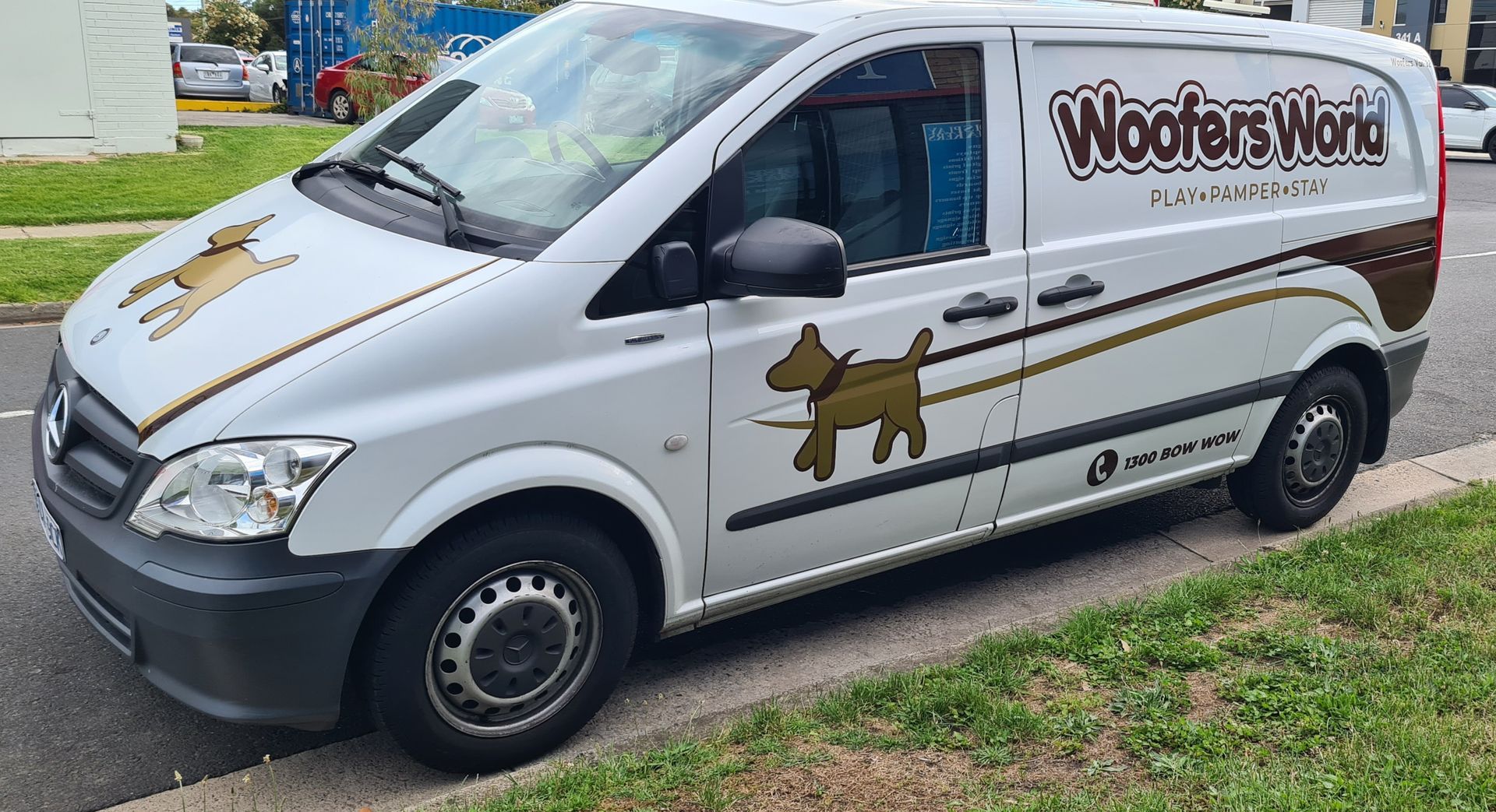 A white van with a dog on the side is parked on the side of the road.