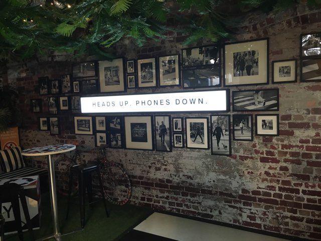 A brick wall with a sign that says heads up phones down