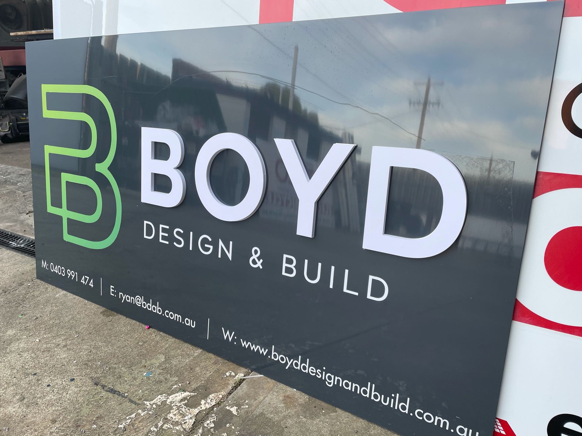A sign for boyd design and build is sitting on the ground.