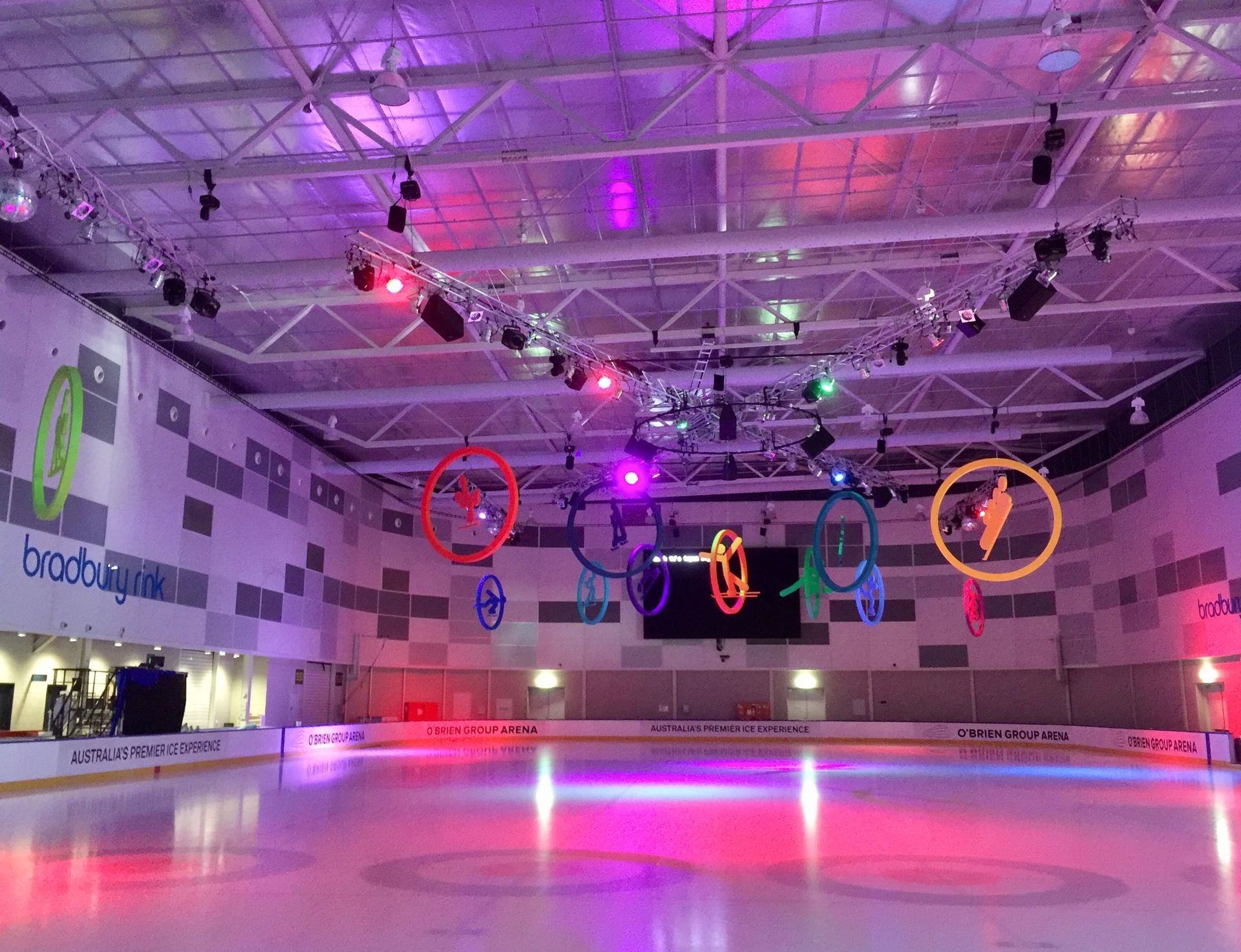A large indoor ice rink with a lot of lights on it.