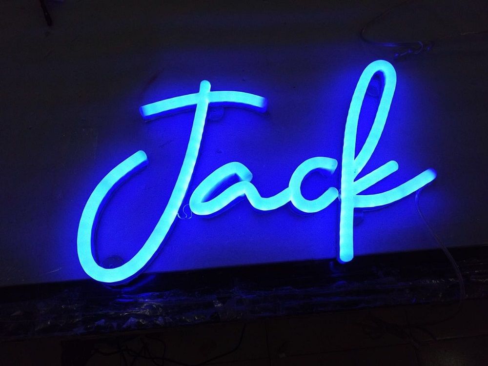 A neon sign that says jack is lit up at night.