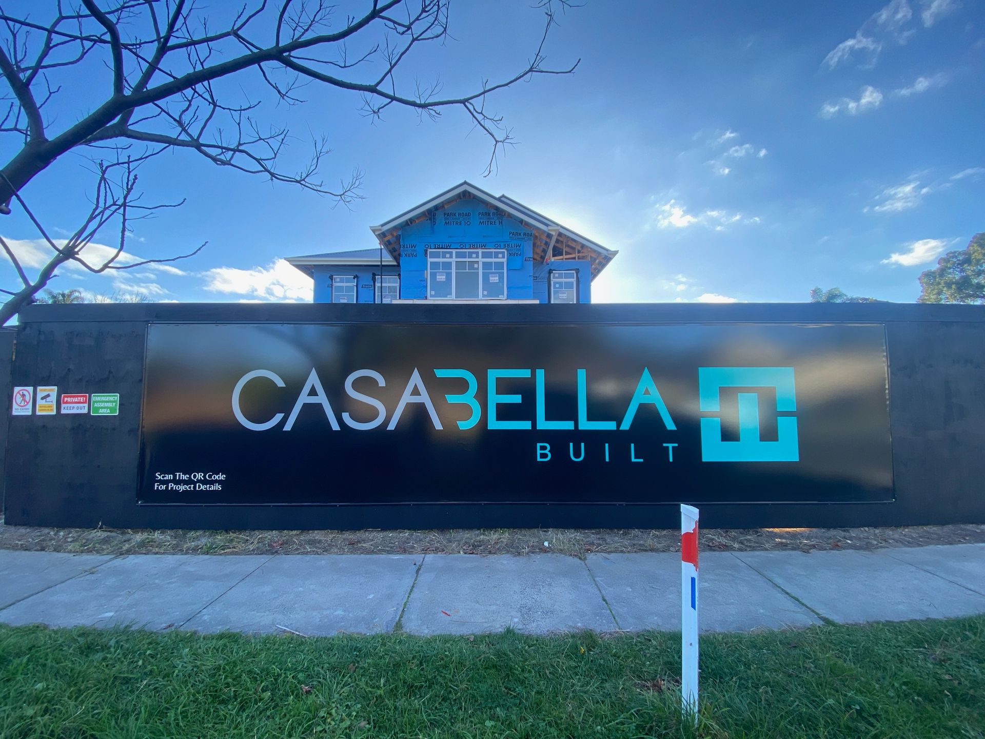 A large black sign that says casabella built in front of a house under construction.