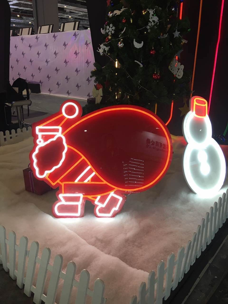 A neon sign of a pig and a snowman in front of a christmas tree