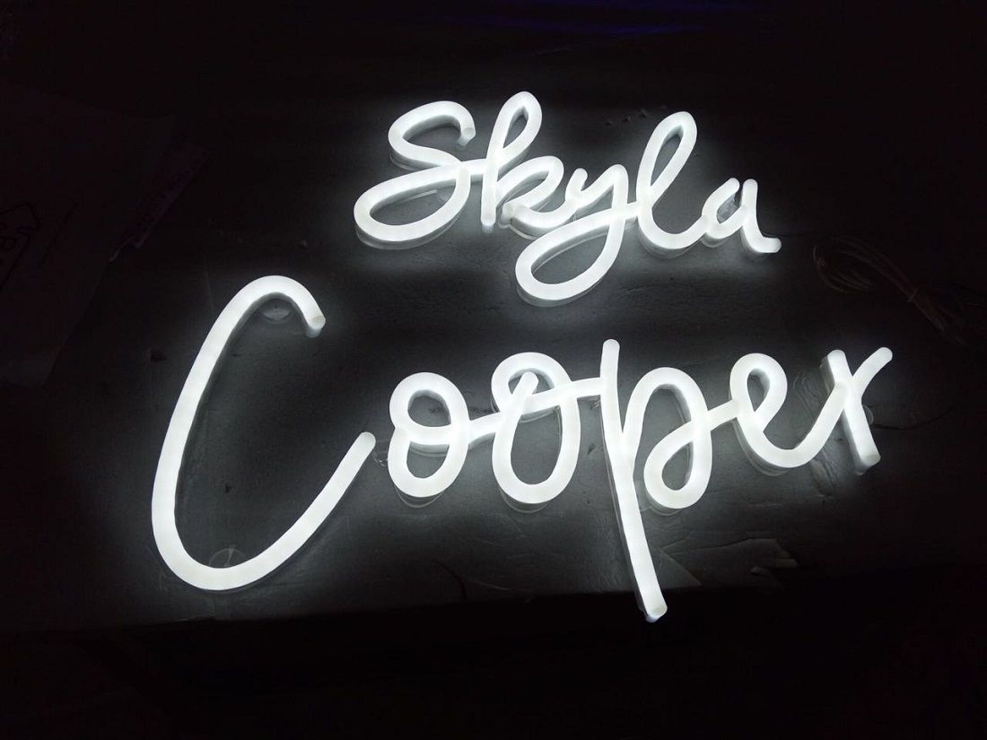 A neon sign that says skyla cooper on a black background.