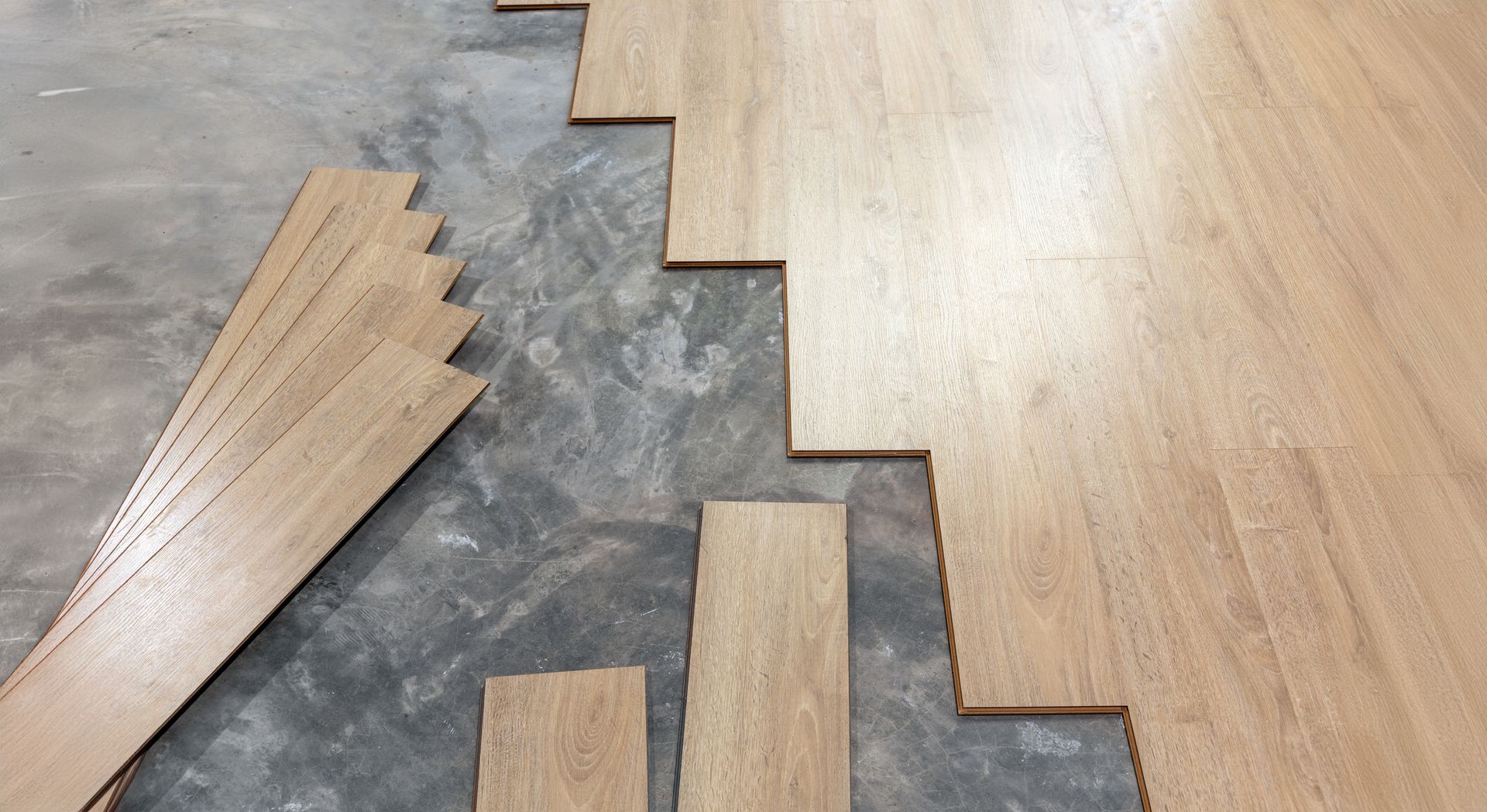 A wooden floor is being installed on a concrete floor.