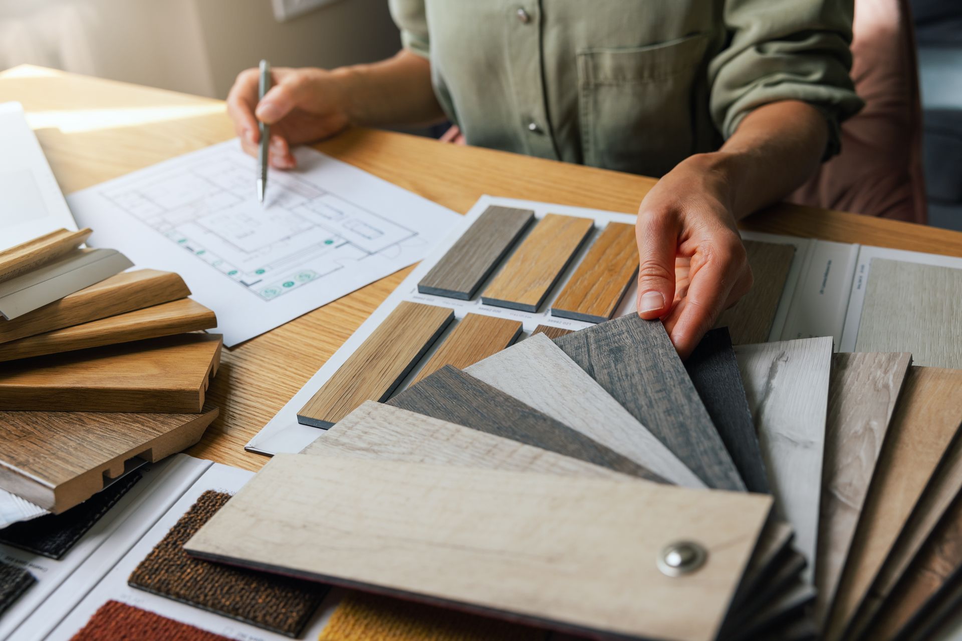 A woman is sitting at a table looking at samples of wood and fabric.