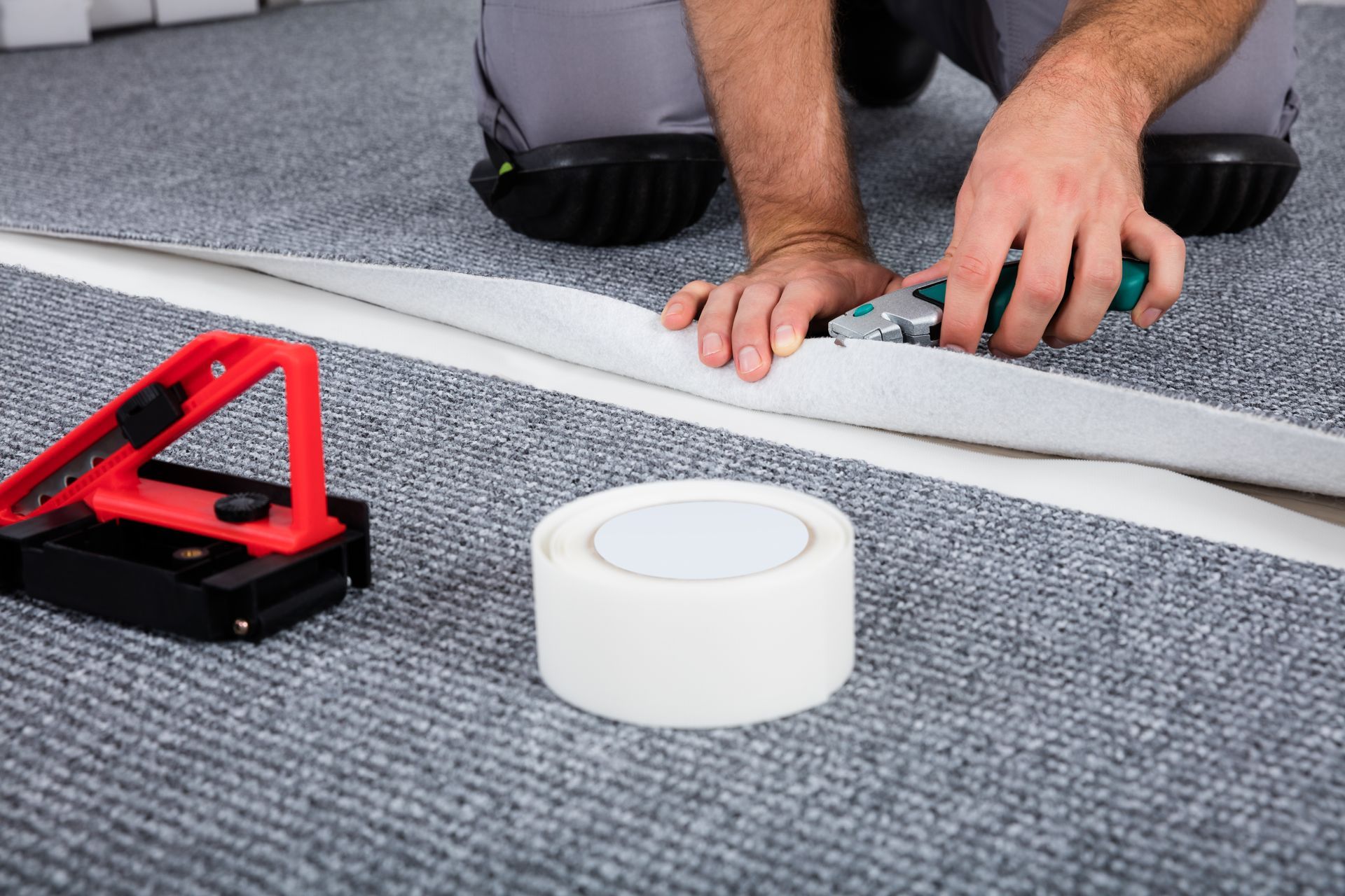 A man is cutting a piece of carpet with a pair of scissors.