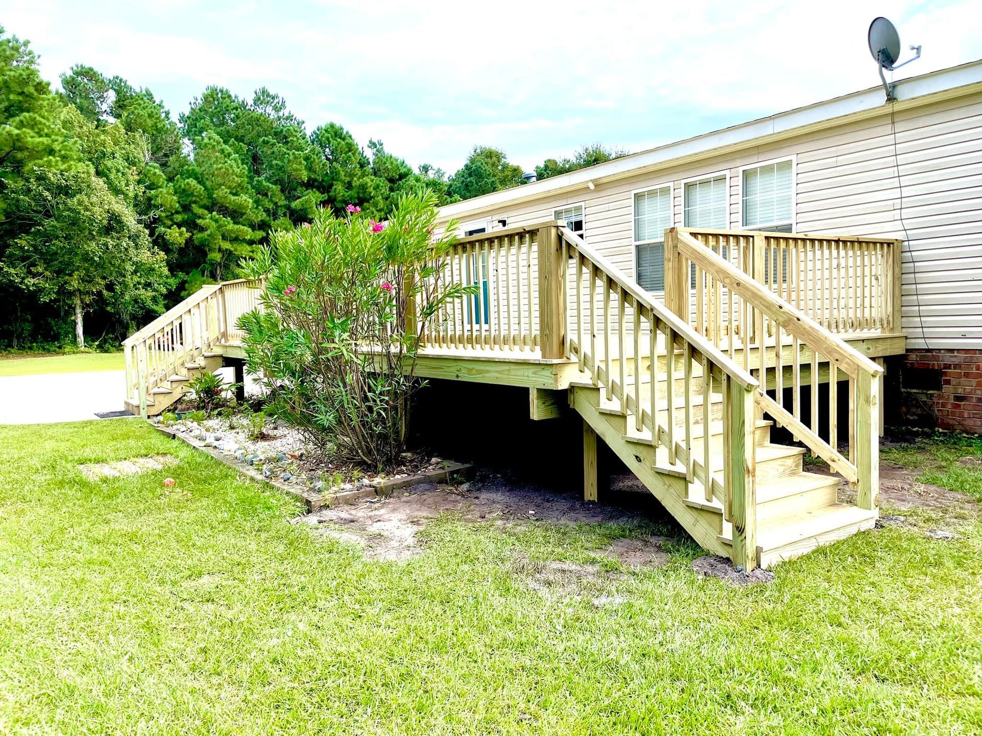 A mobile home with a wooden deck and stairs.