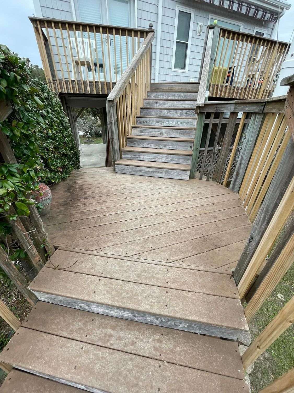 A wooden deck with stairs leading up to it and a house in the background.