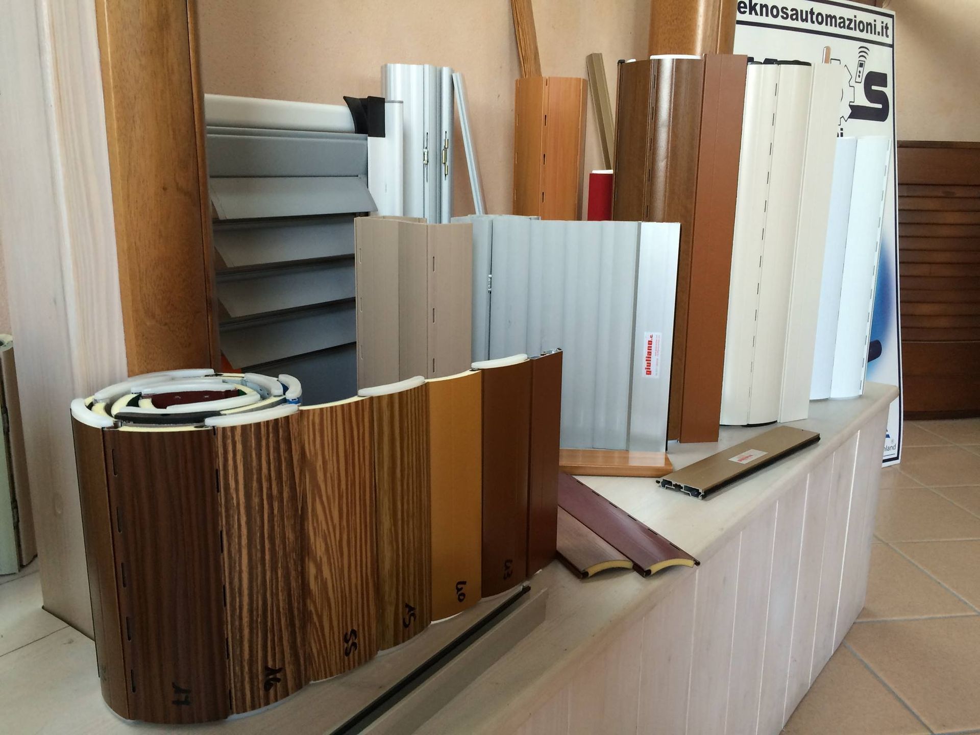 Esposizione di vari materiali da costruzione in legno e di colori neutri, tra cui pannelli e finiture, in uno showroom.