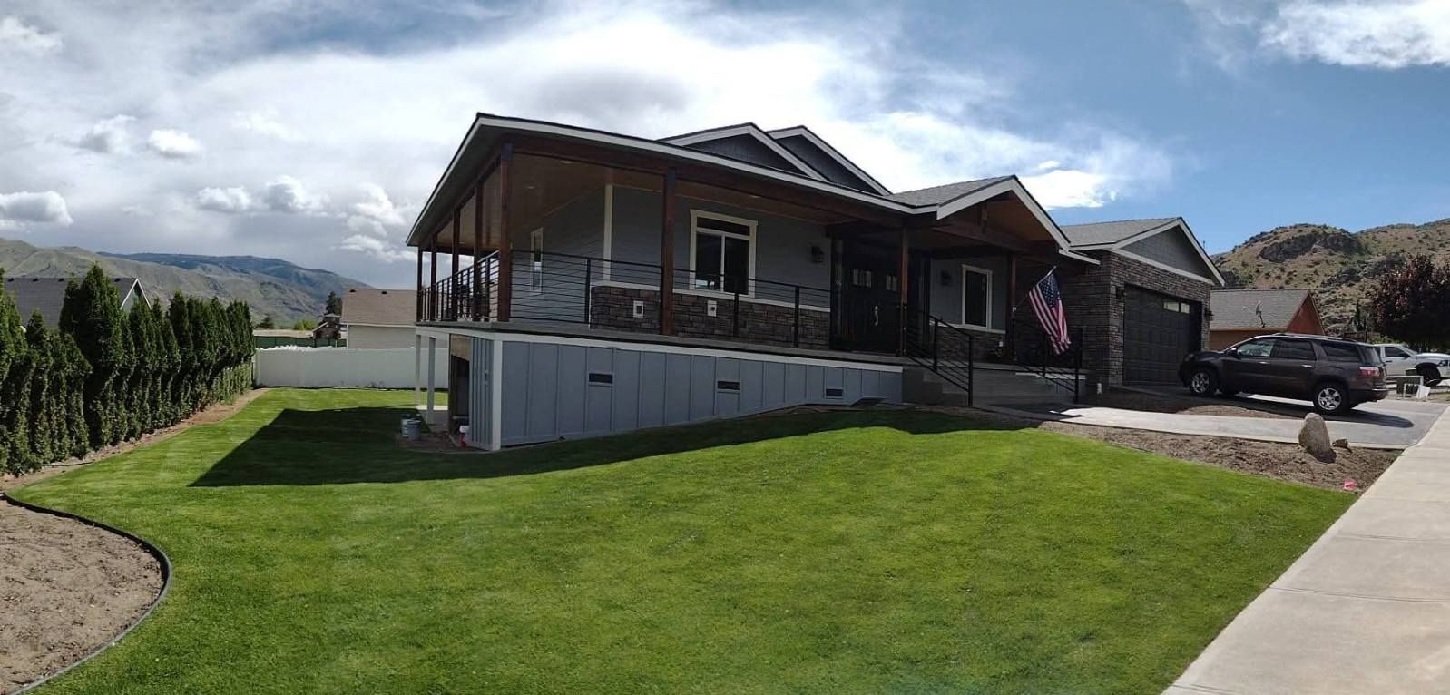 A residential home features a long, modern ramp leading to the front porch, set against a backdrop of rolling hills.