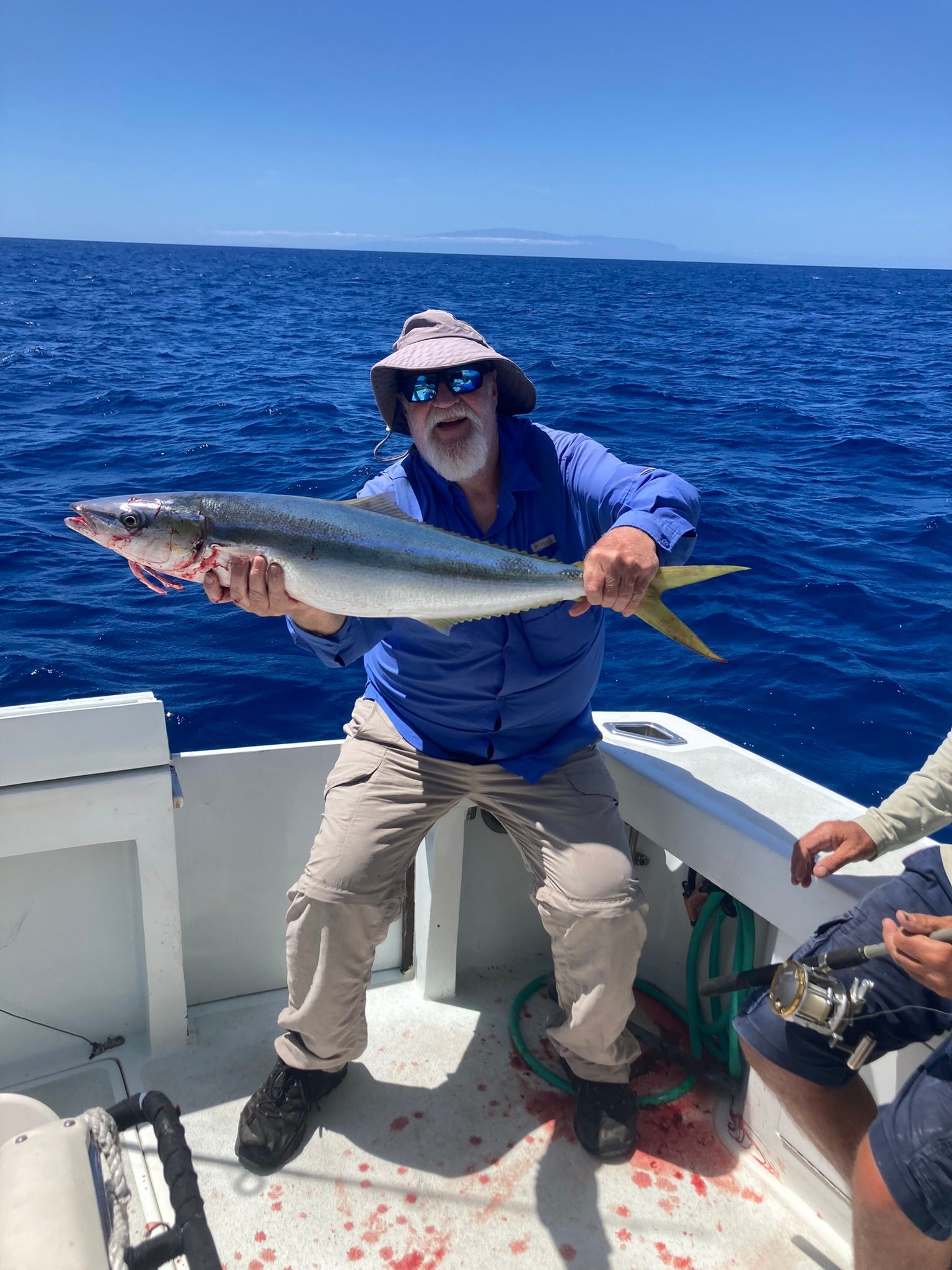 A man is sitting on a boat holding a fishing rod