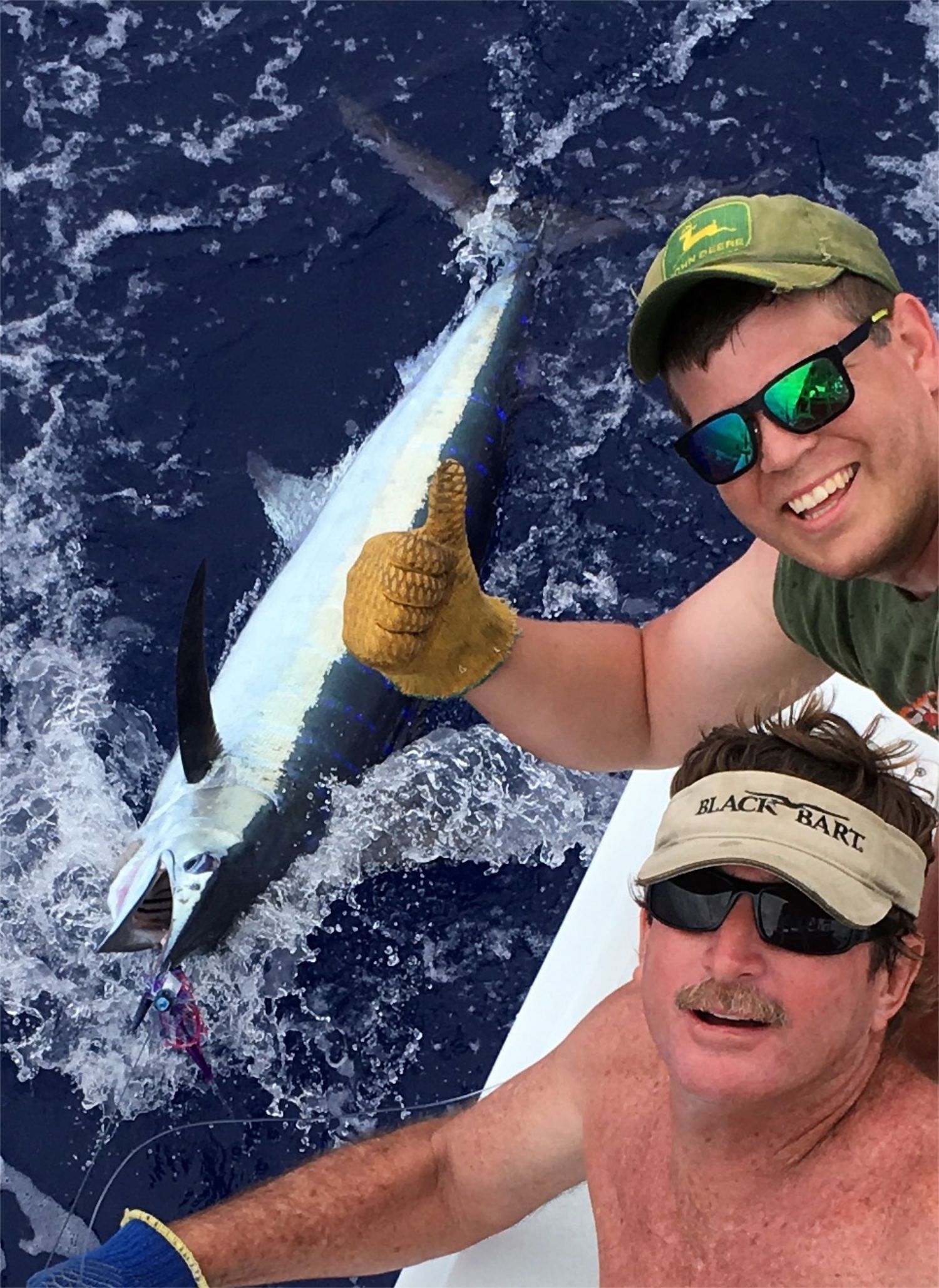 A man is holding a fish on a boat in the ocean.