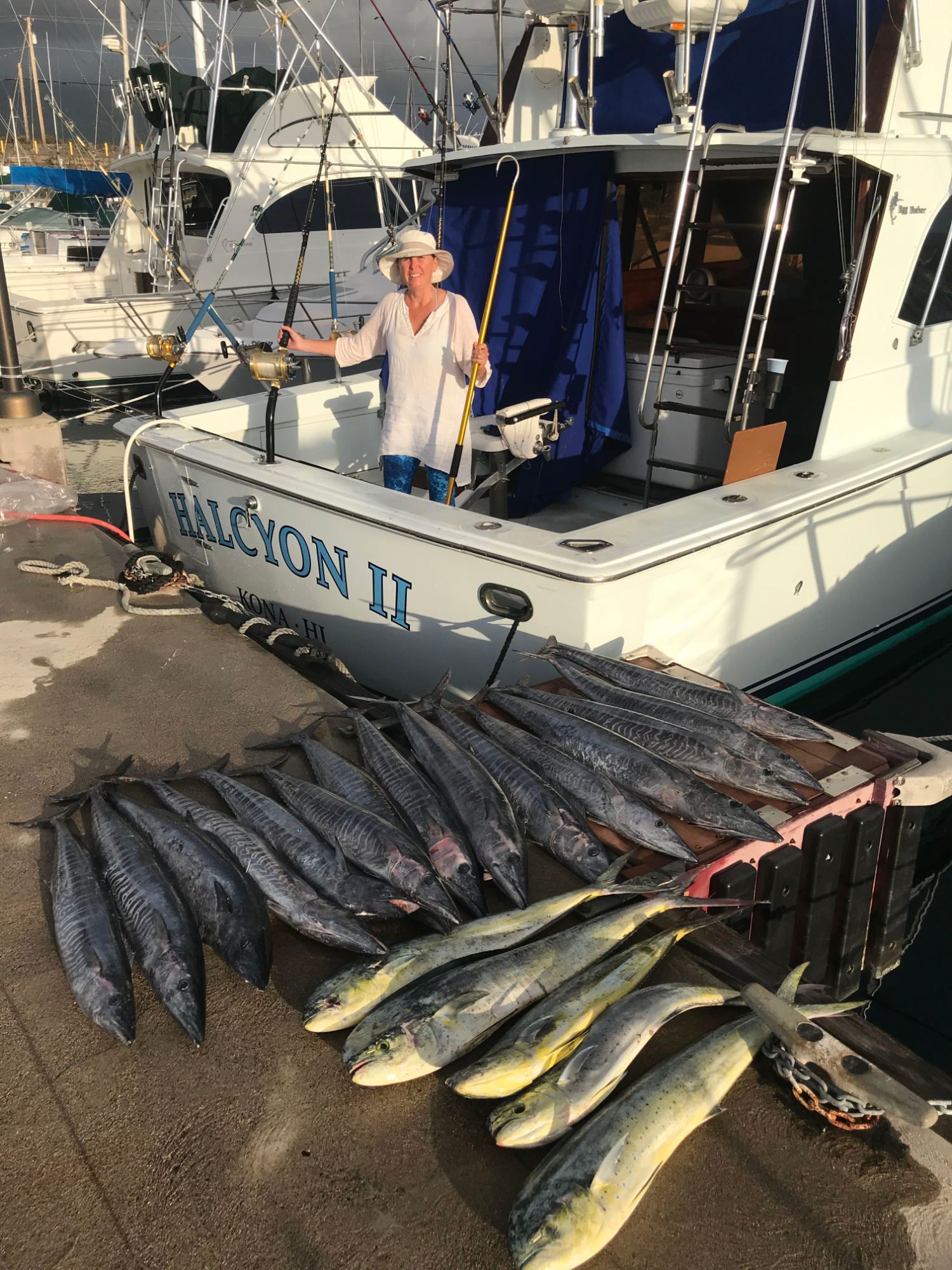 A man is standing next to a boat filled with fish.