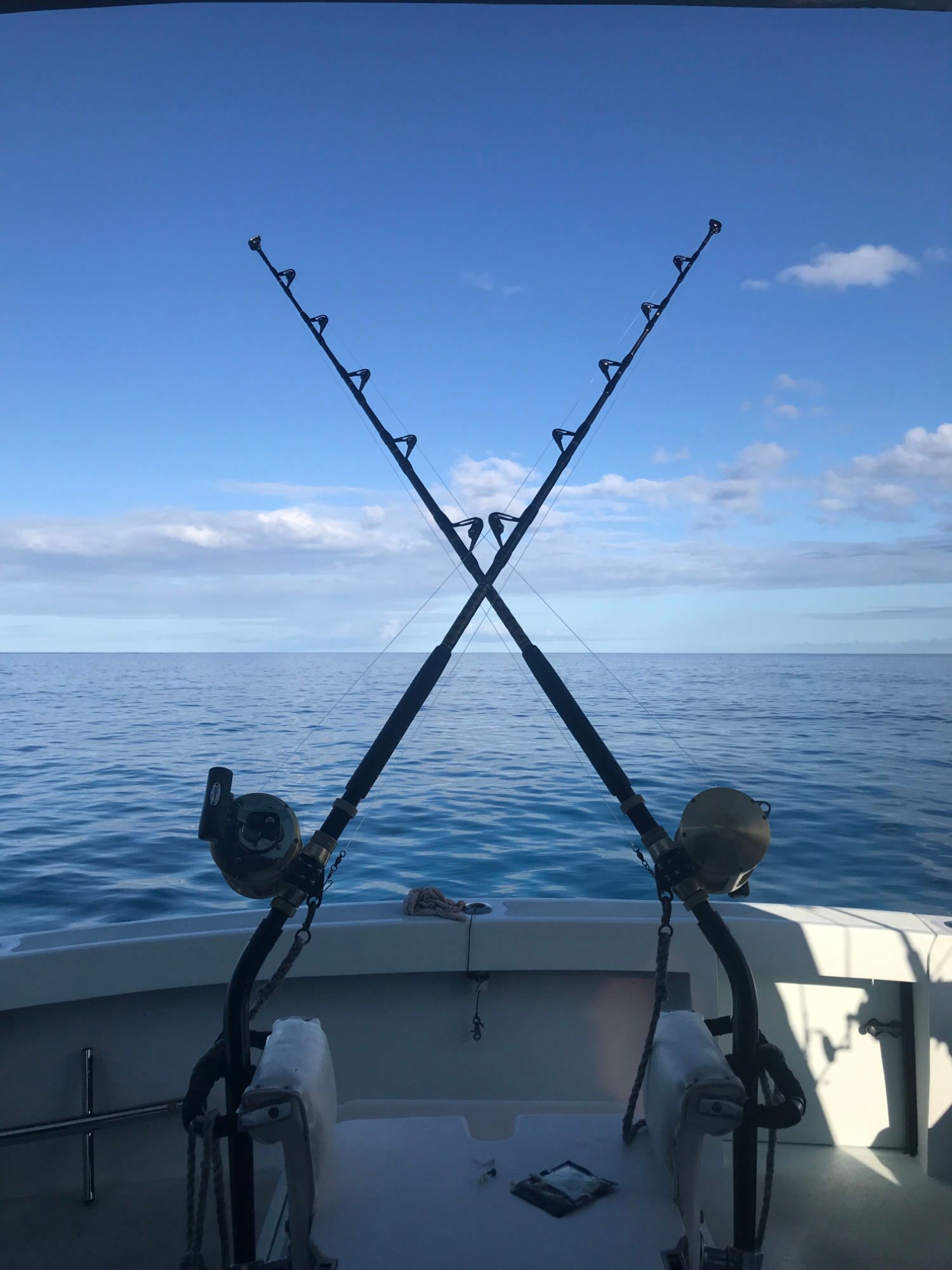 Two fishing rods are crossed over each other on a boat in the ocean.