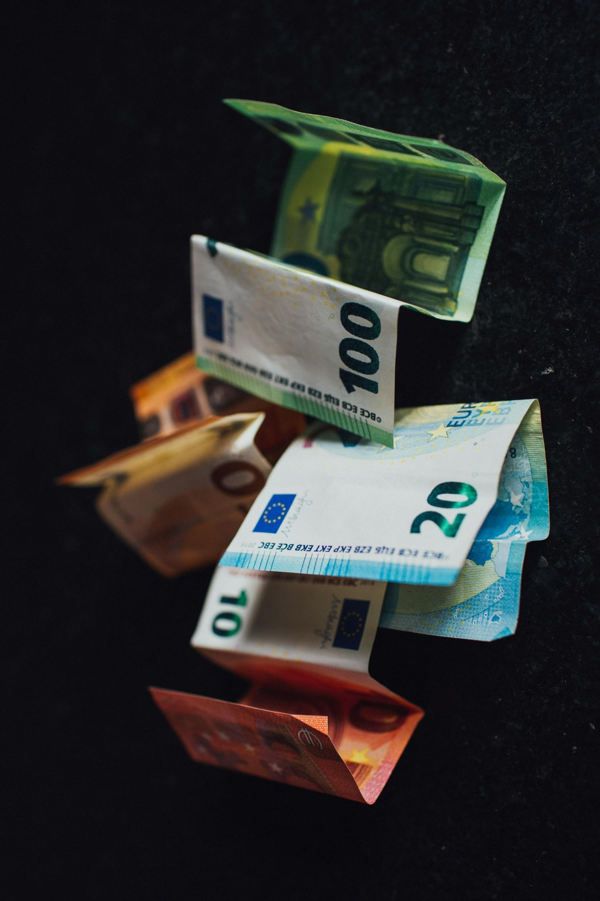 Een stapel eurobankbiljetten die drijft op een donkere achtergrond.
