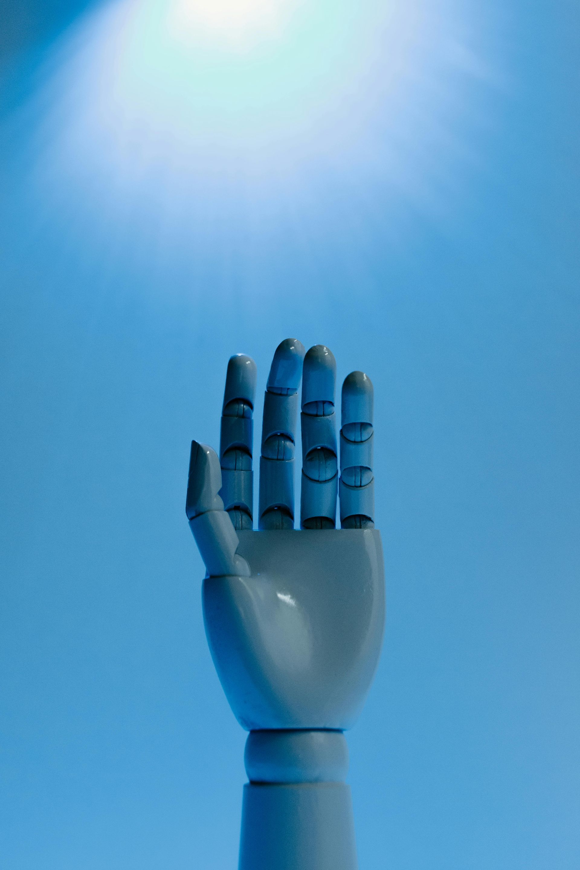 Een opgeheven robotarm die reikt naar het felle zonlicht tegen een blauwe hemel.