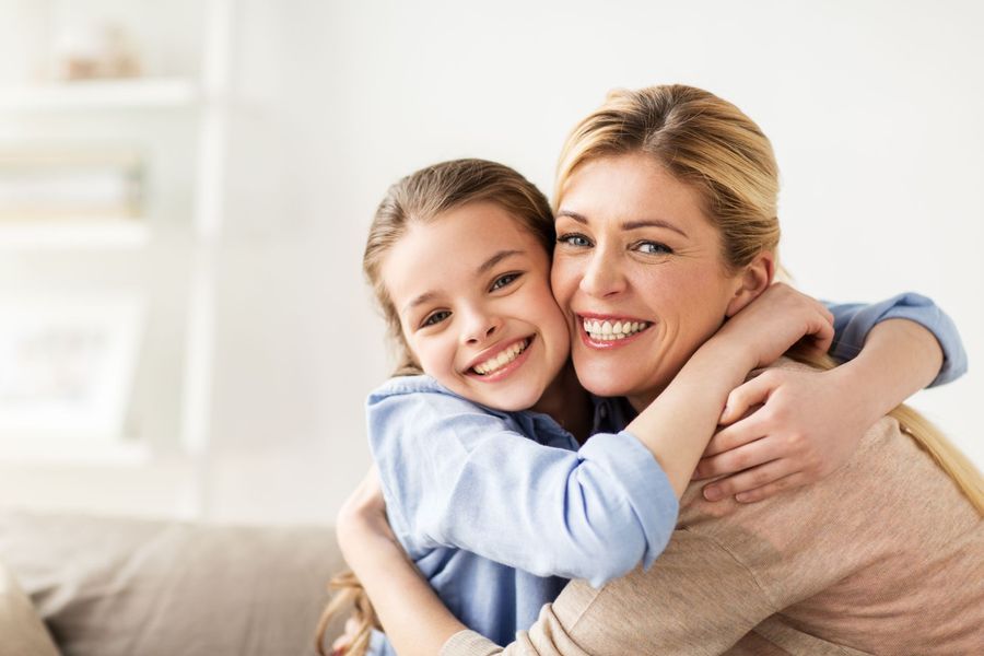 Smiling woman and child hugging on a couch in a bright living room