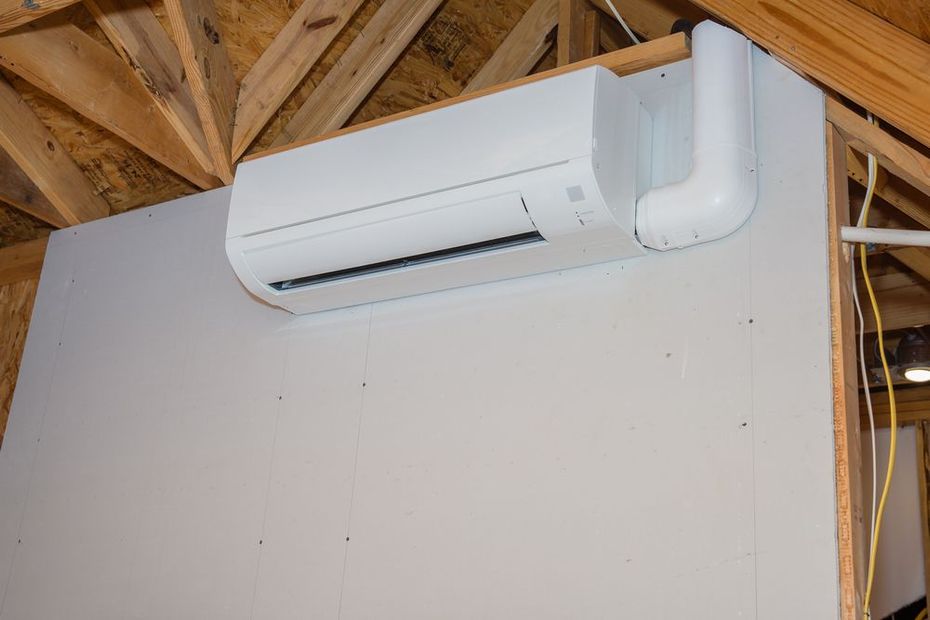 White wall-mounted mini-split air conditioner near exposed wooden ceiling beams.