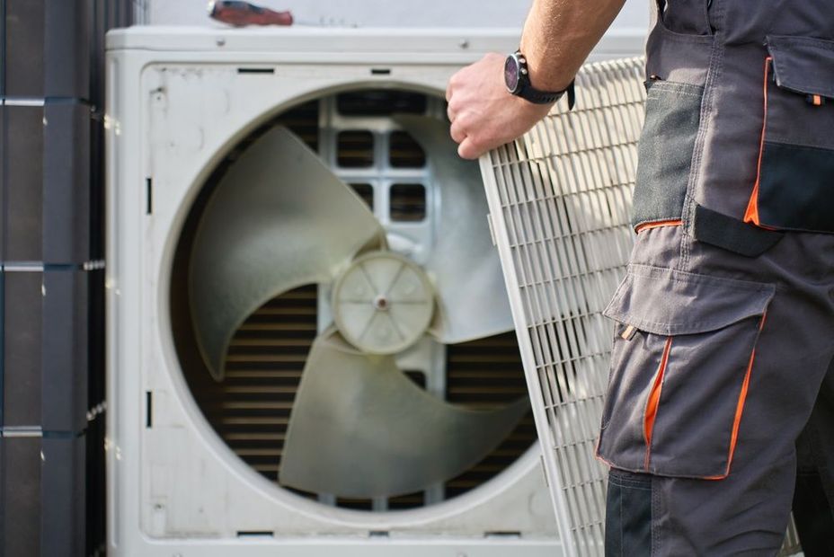 Technician inspecting an outdoor air conditioner unit with the cover removed