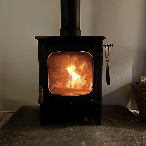 Black wood stove with a bright fire burning inside in a simple room