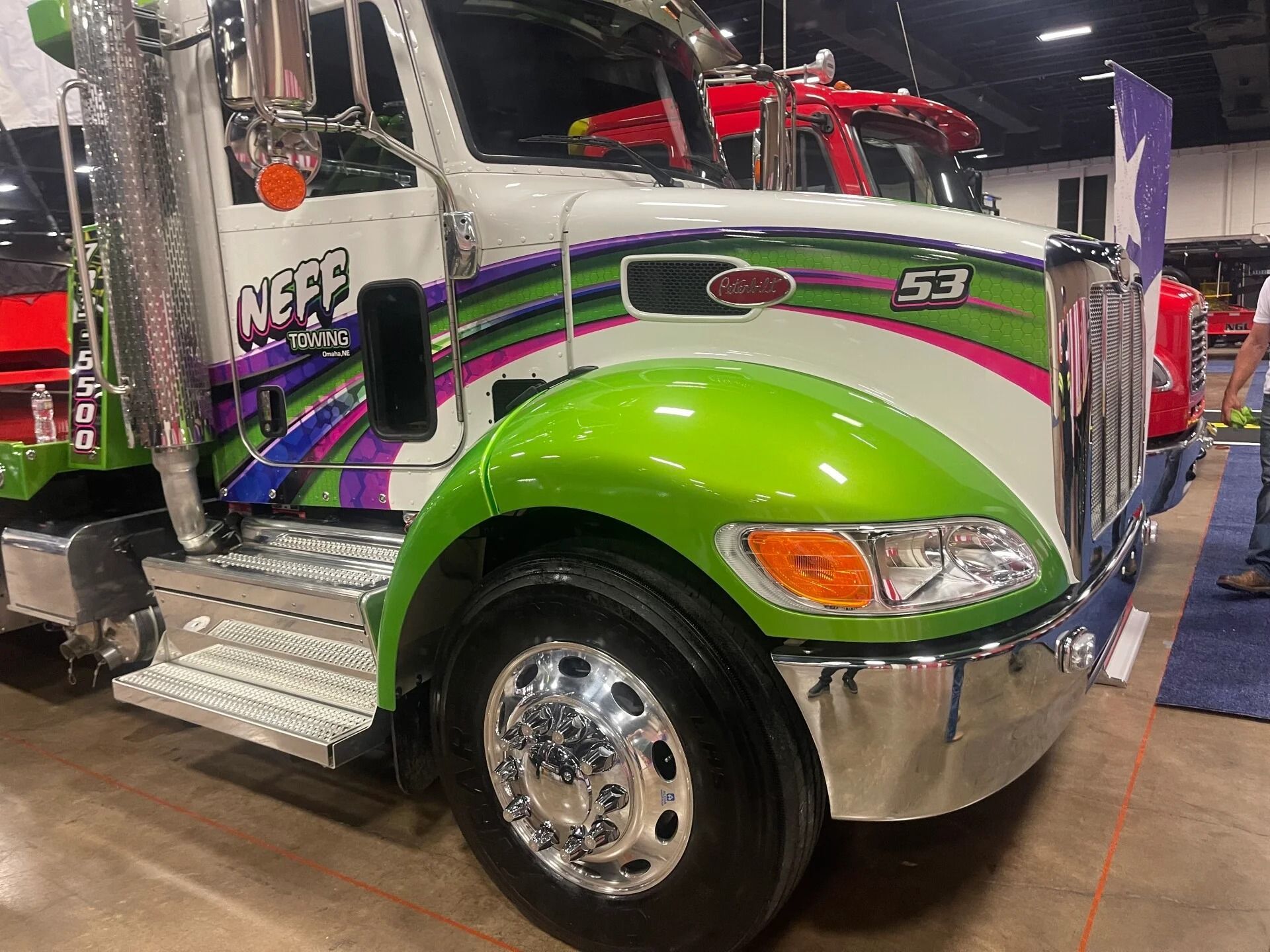 Green and chrome semi truck on display at an indoor show with purple and white striping.