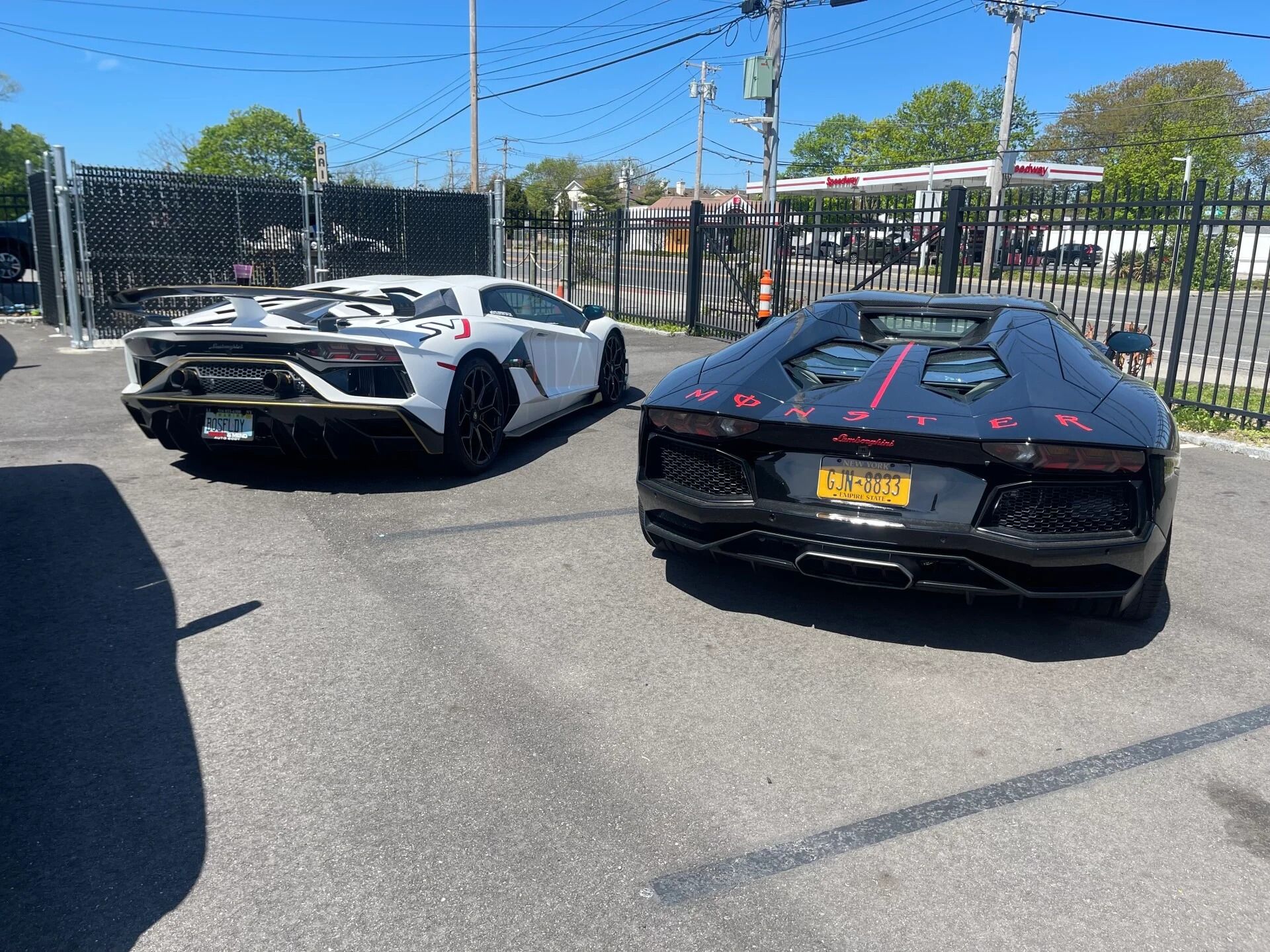 Two Lamborghini supercars parked in a lot, one white and one black with red accents.