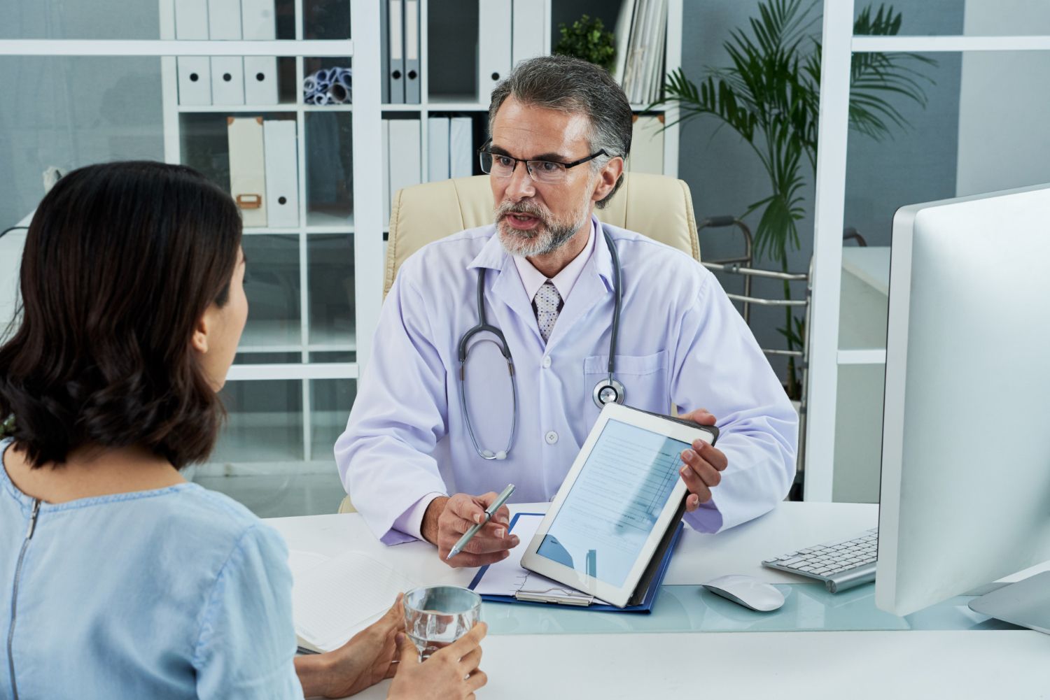 Doctor showing a clipboard chart to a patient in a bright clinic office