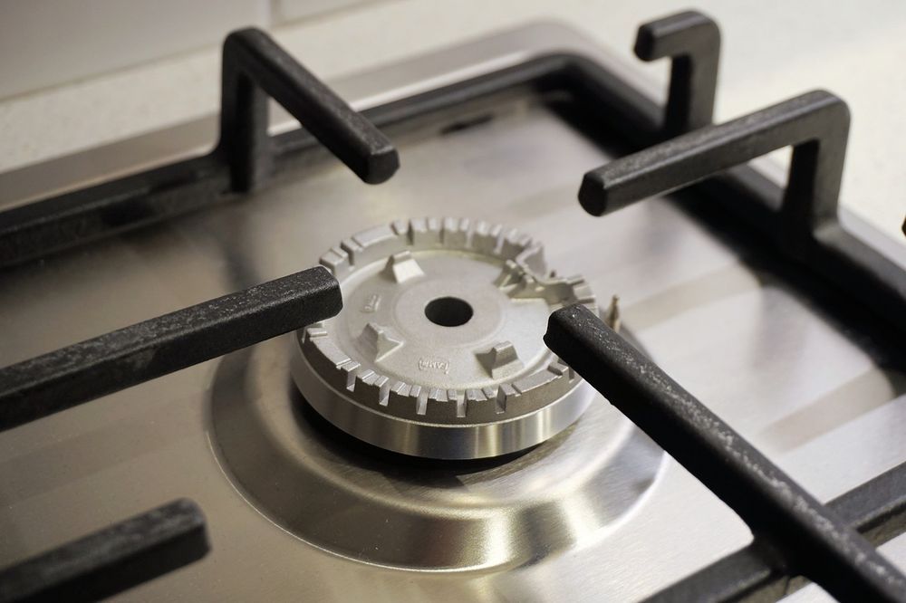 Close-up of a stainless steel gas stove burner and black grates.
