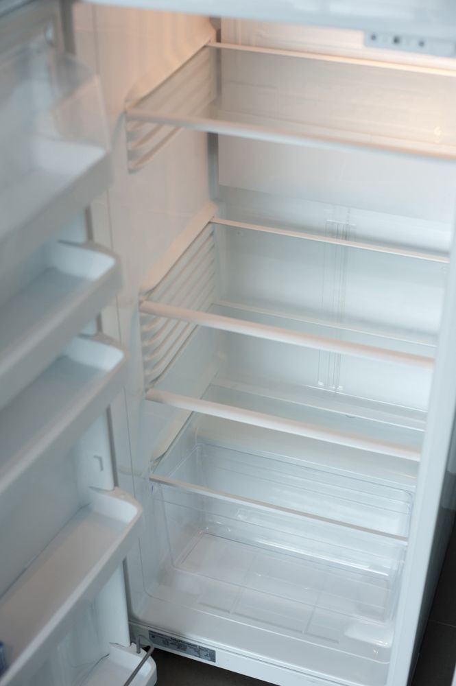 Empty white refrigerator interior with several shelves.