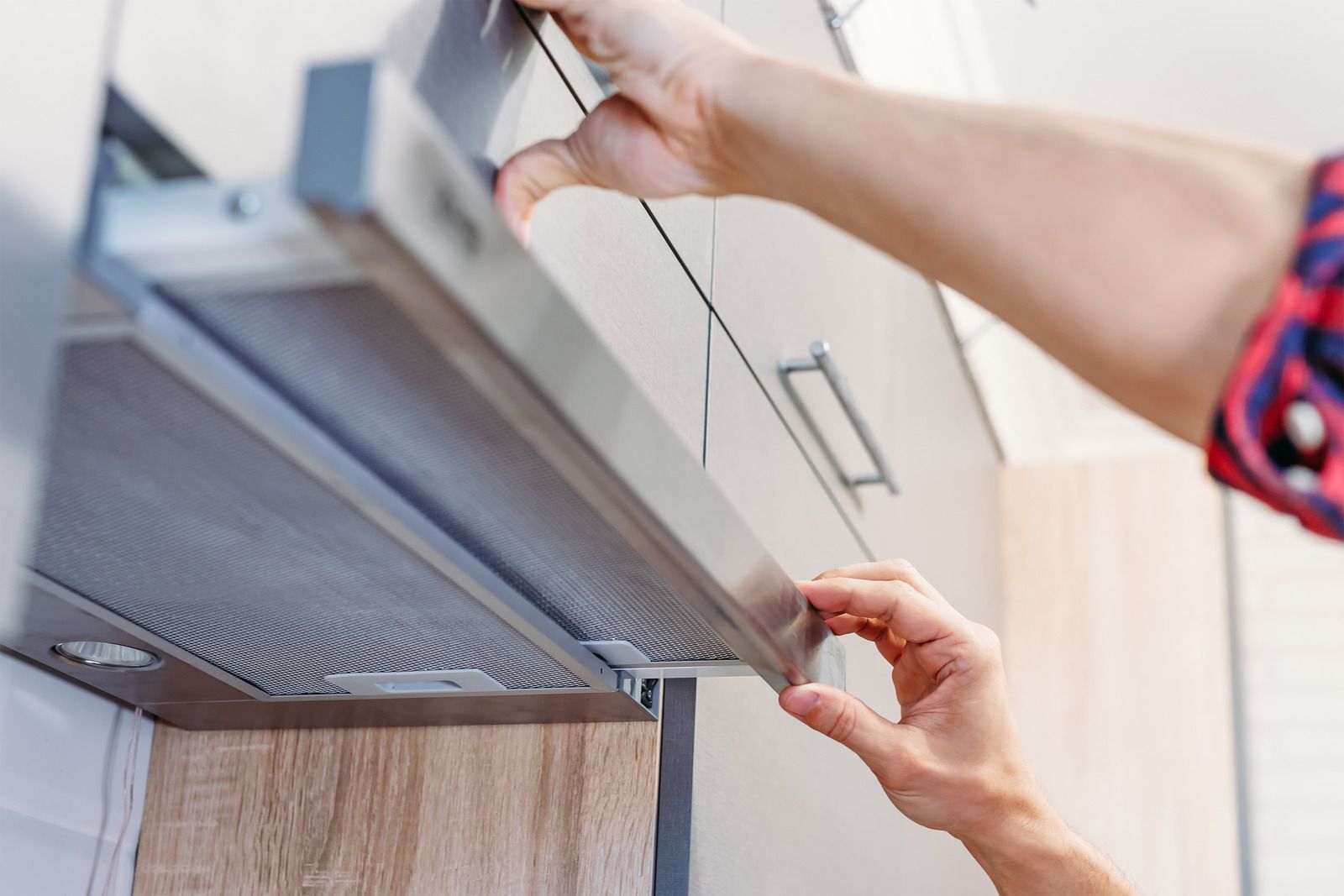 Person removing a kitchen range hood filter.