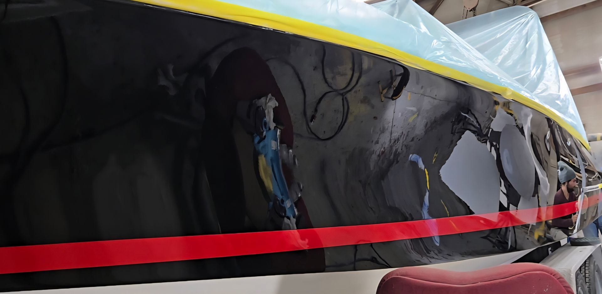 A close-up view of an aircraft fuselage under repair, featuring exposed dark interior components, wiring, and masking tape.