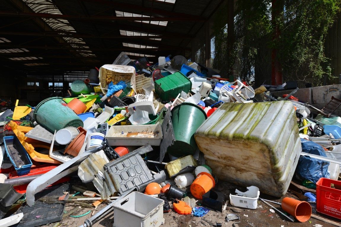 Piles of mixed trash and broken containers scattered in a dim industrial area