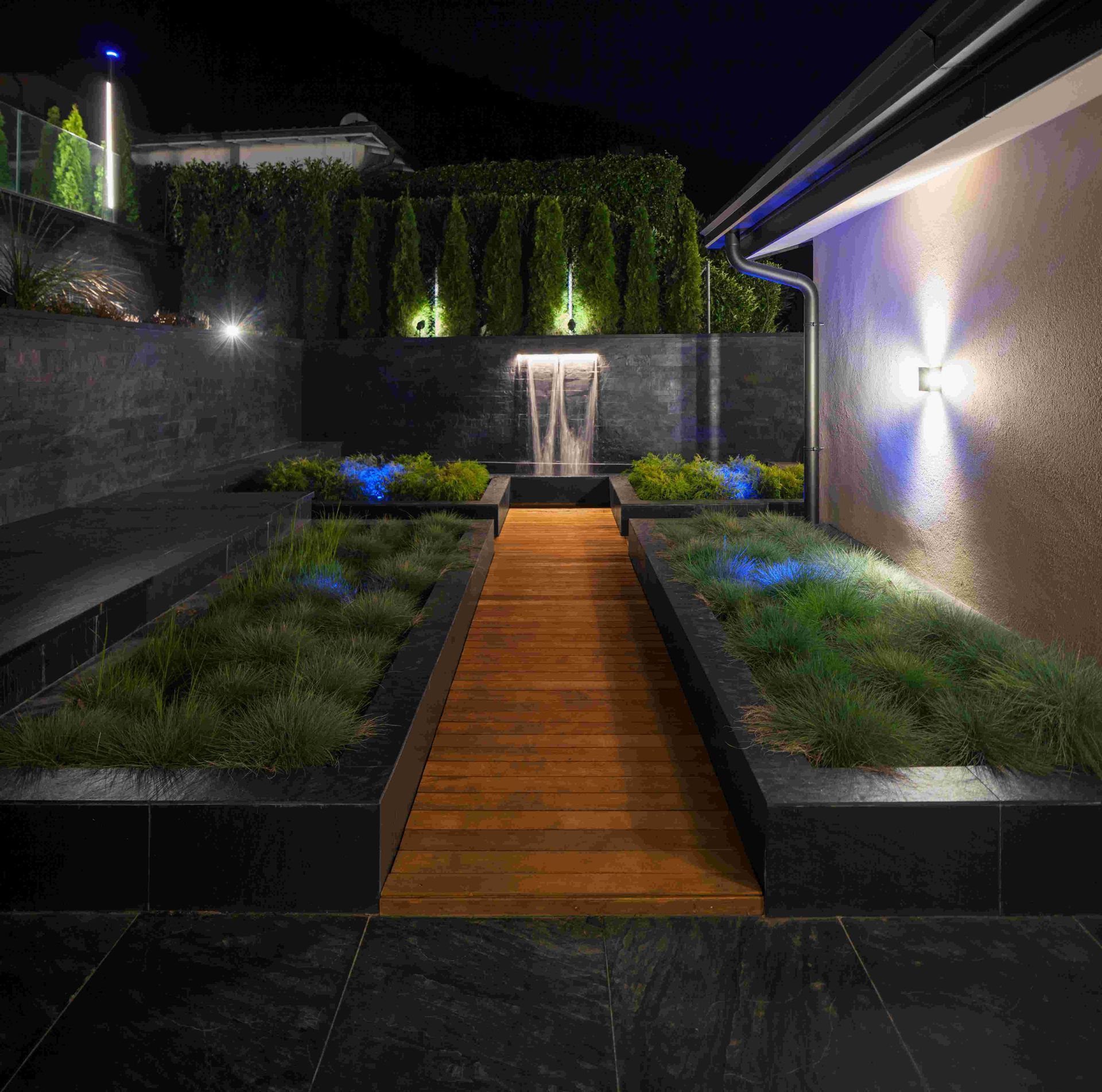 Lights outside of a house at night by the deck and walkway