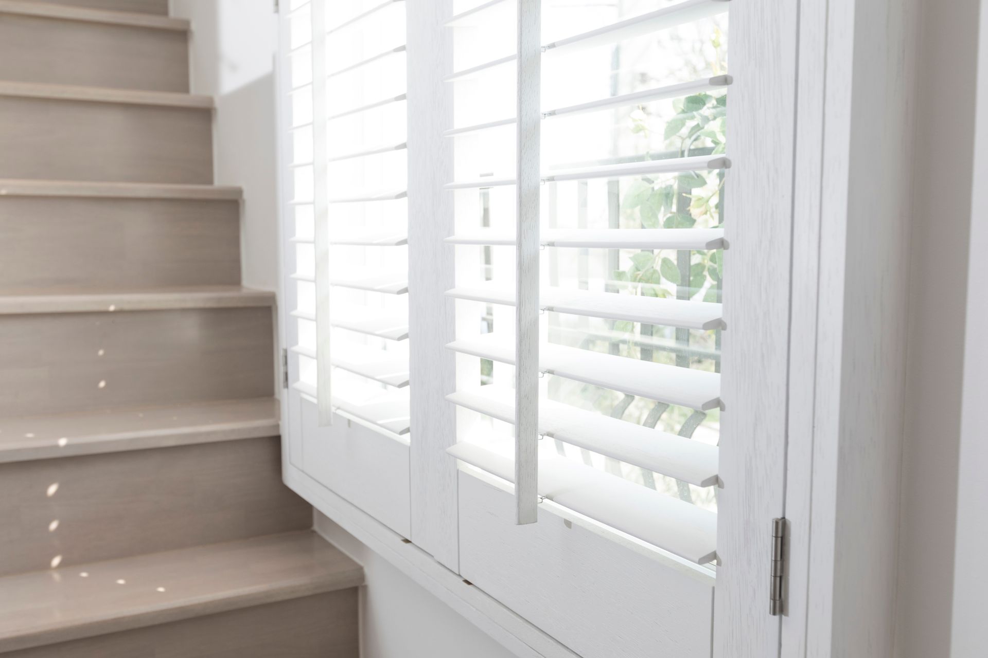 Close-up view of window shutters with horizontal blinds next to a set of steps.