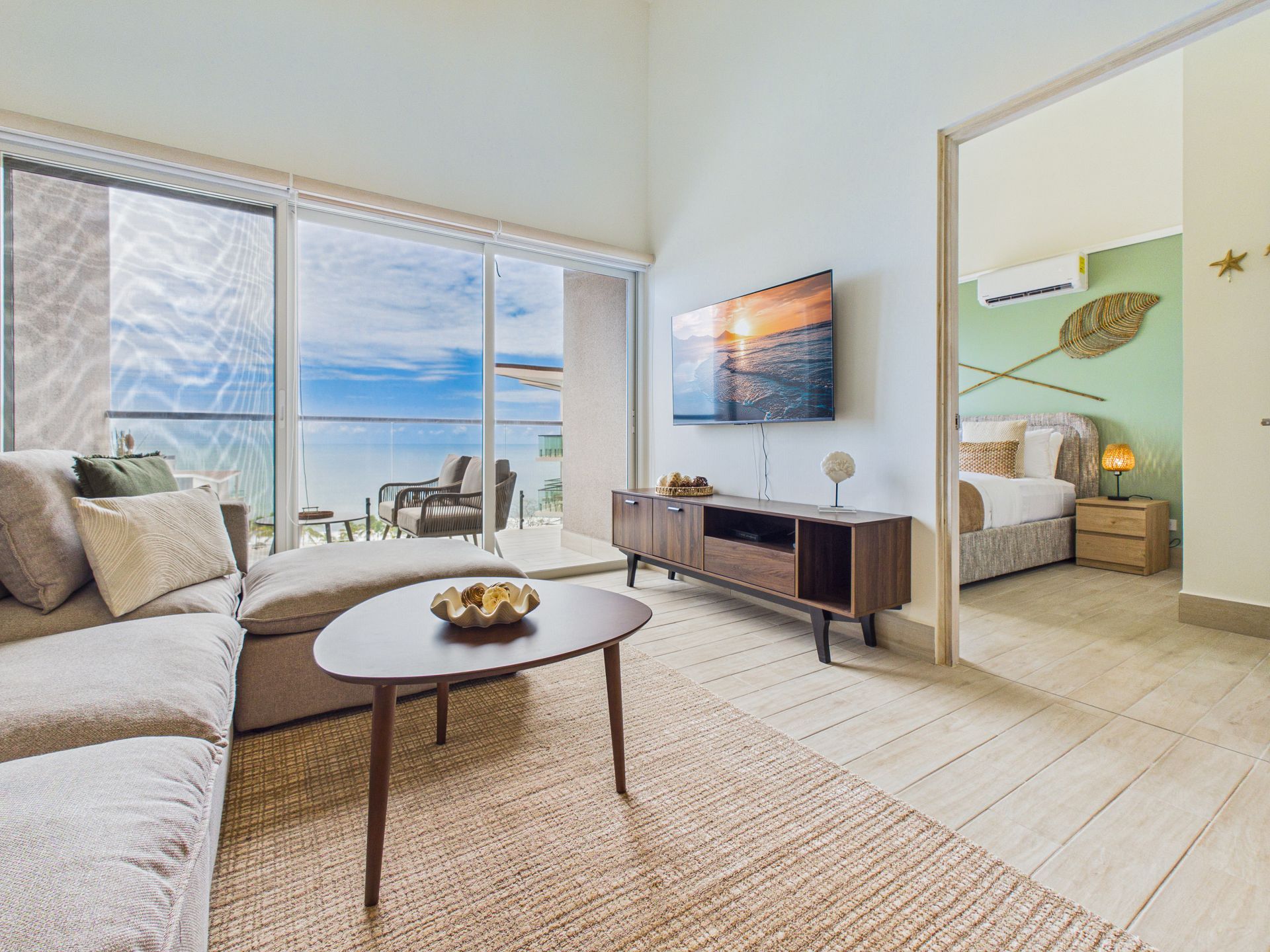 Sala de apartamento en Playa Caracol con consola de medios y vista hacia la recámara principal — fotografía para listing de venta en Relocation Panama.