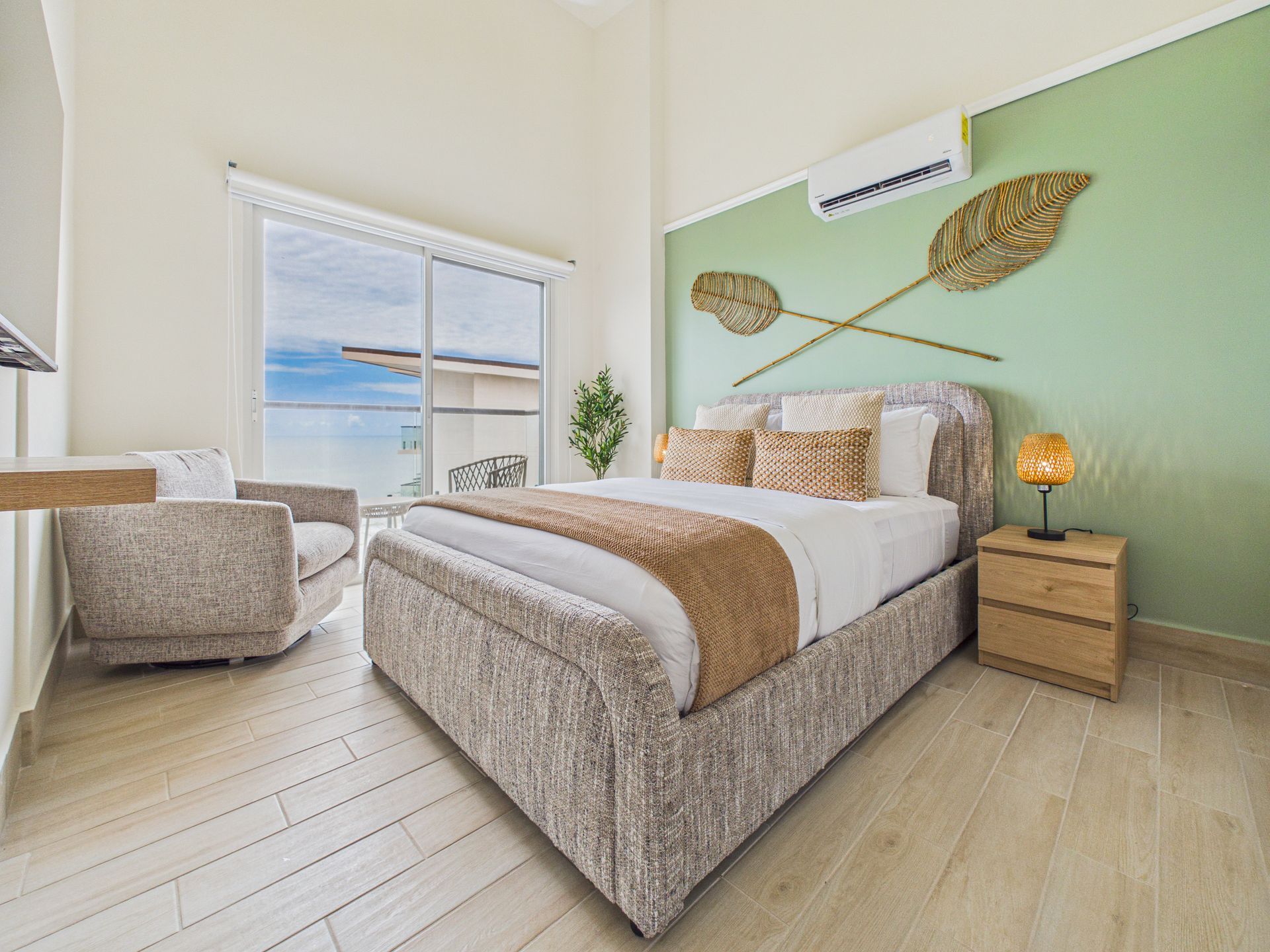 Recámara principal de apartamento en Playa Caracol con cabecera tapizada y ventanal — fotografía inmobiliaria para Relocation Panama.