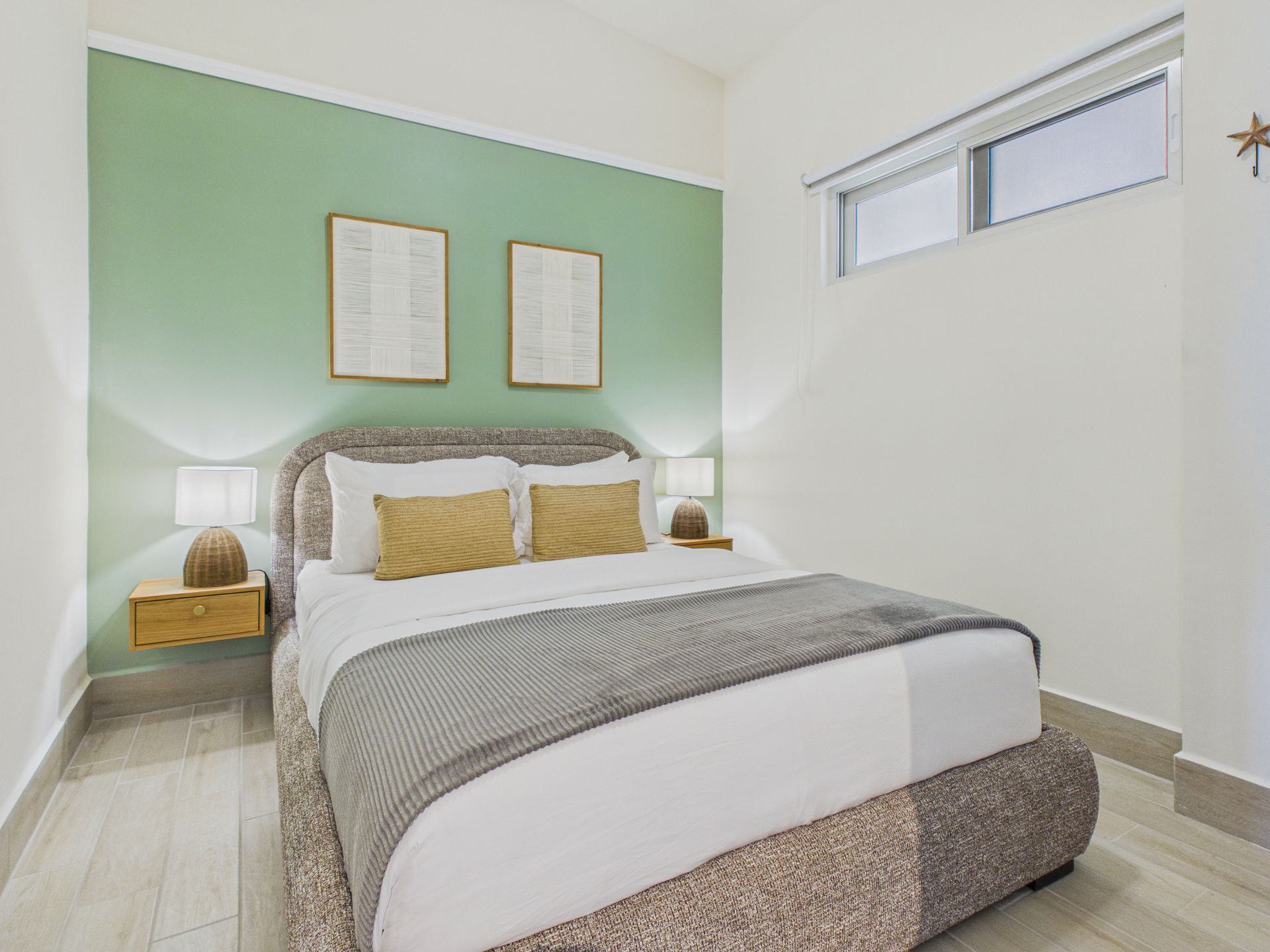 Segunda recámara de apartamento en Olas 4, Playa Caracol, con pared verde de acento y doble cama — listing de venta en Relocation Panama Real Estate.