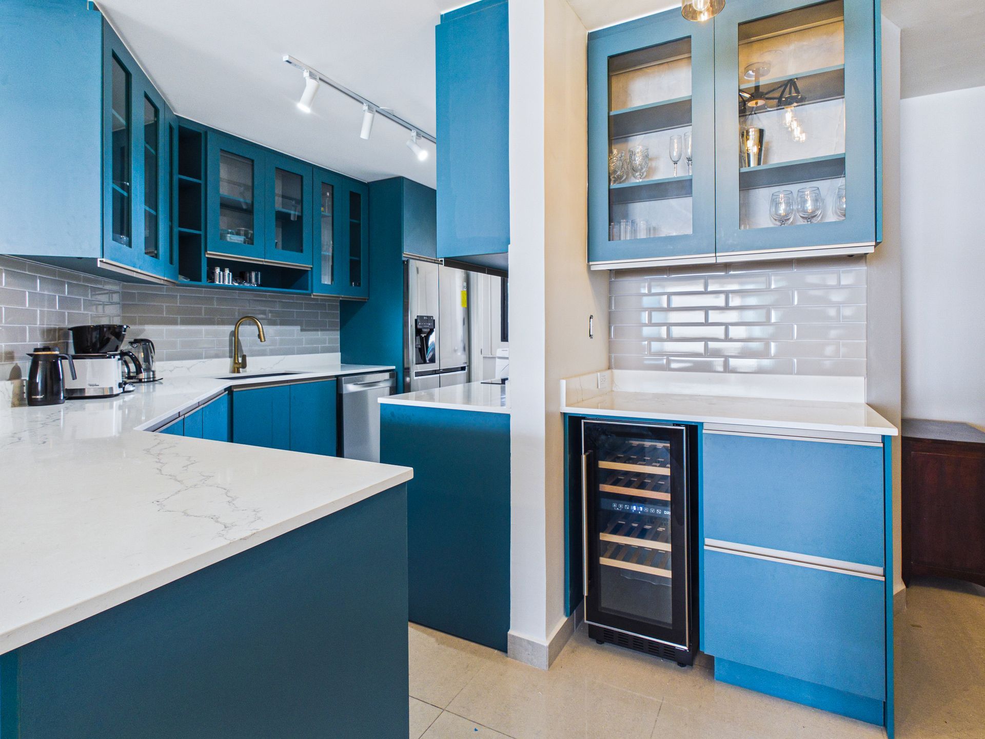 Cocina moderna en azul y blanco con armarios, encimeras blancas y vinoteca integrada.coronado country club