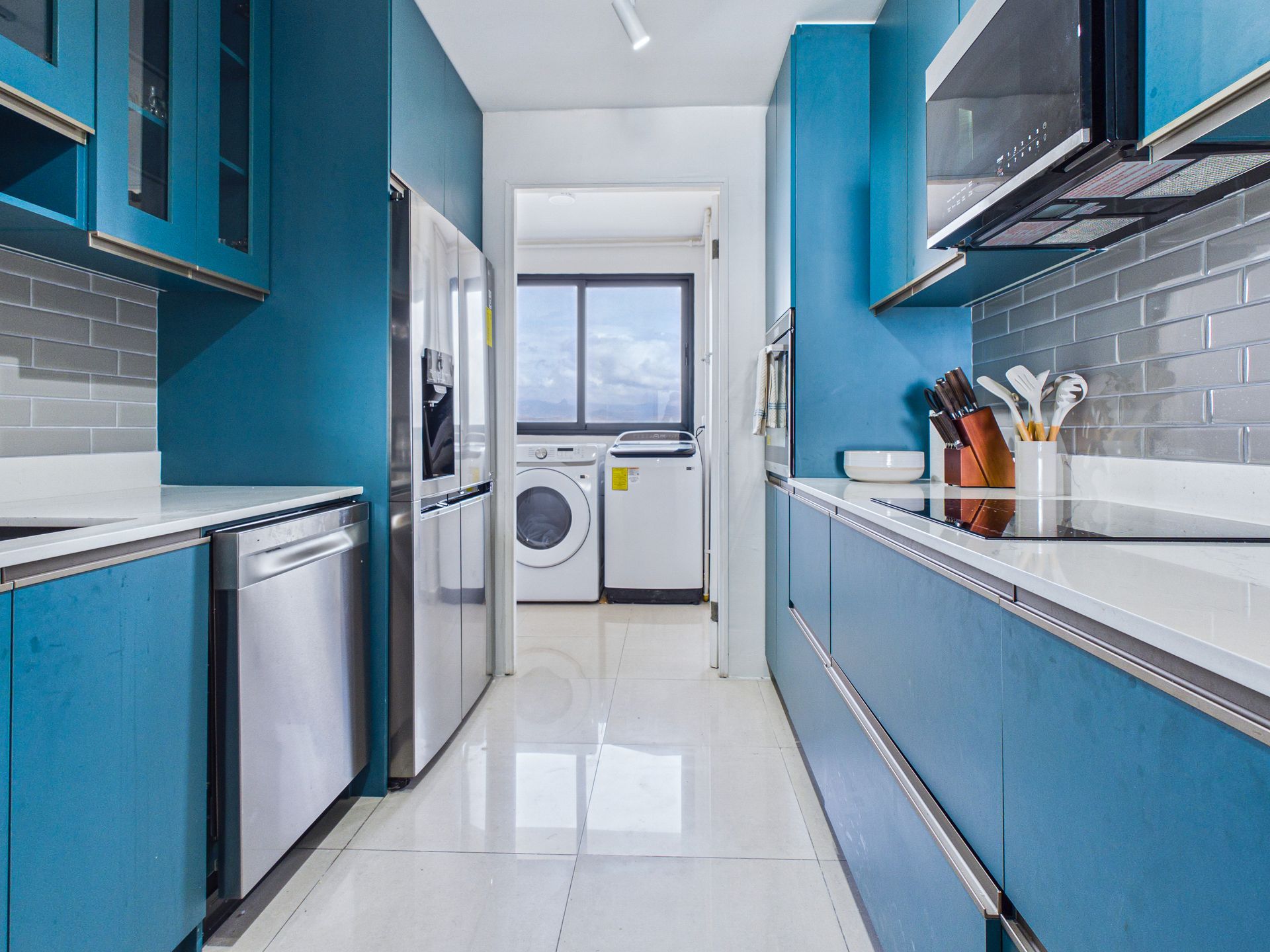 Cocina de color azul brillante con encimeras blancas, electrodomésticos de acero inoxidable y una zona de lavandería al fondo.coronado country club