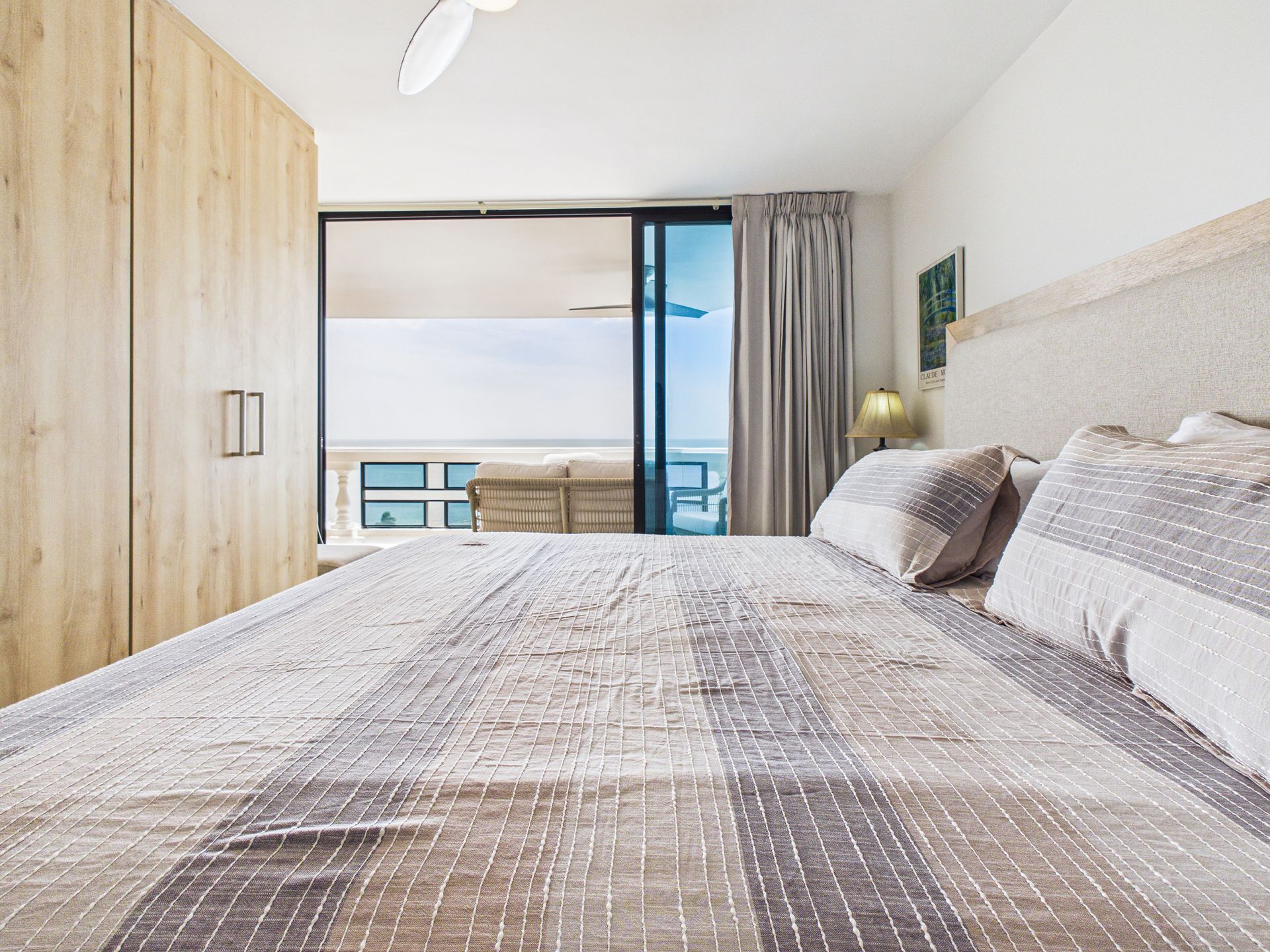 Habitación luminosa con una cama grande, armario de madera y balcón con vistas al océano.coronado country club