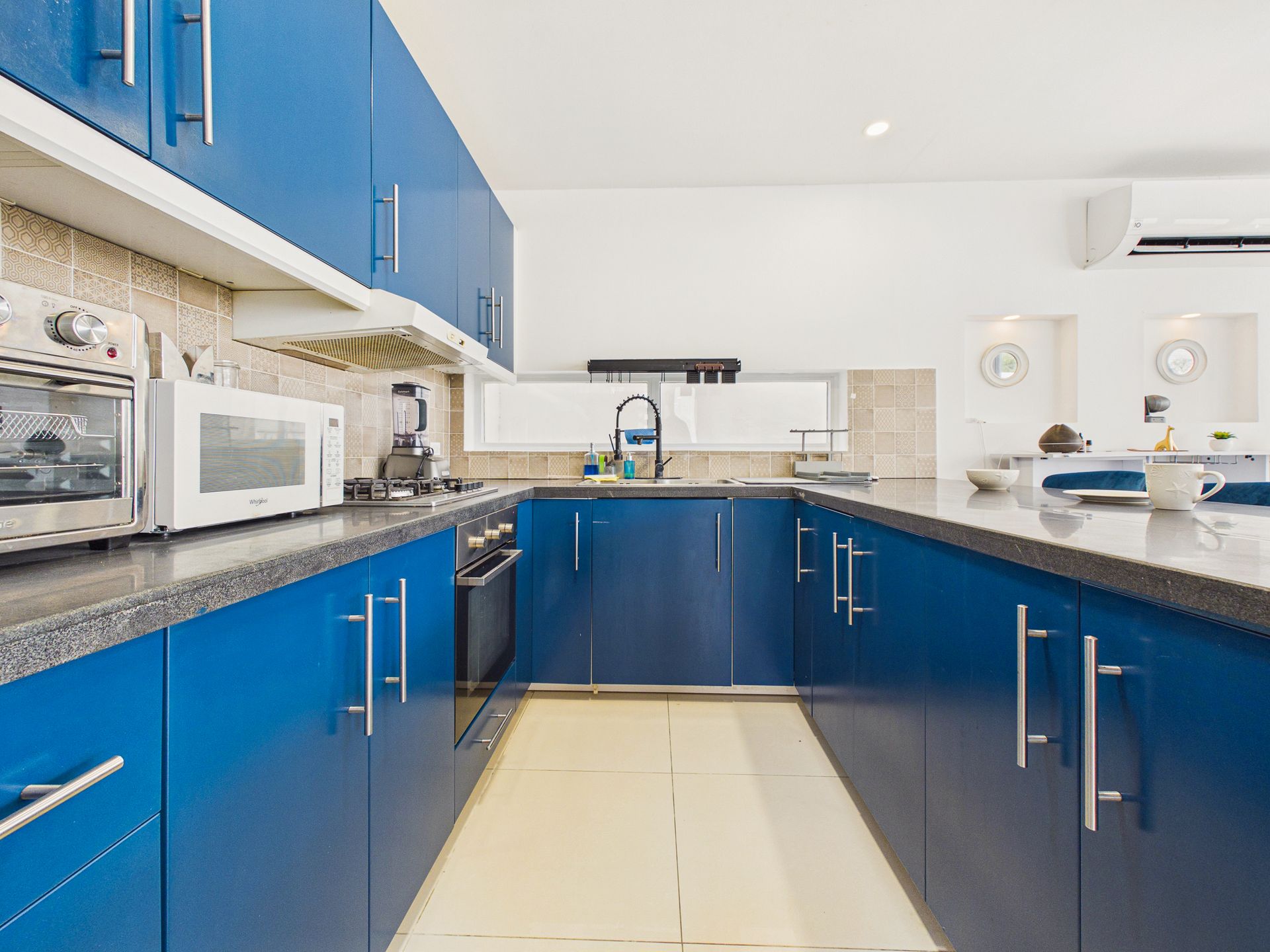 Cocina moderna con gabinetes azules, electrodomésticos de acero inoxidable y una encimera blanca en la isla.