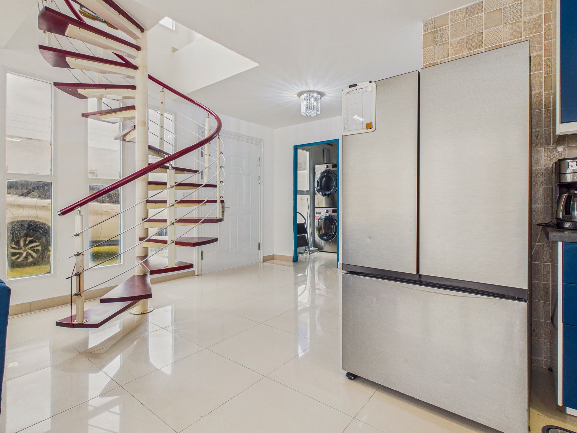 Habitación moderna y luminosa con suelo de baldosas brillantes, escalera de caracol y puerta corredera esmerilada.